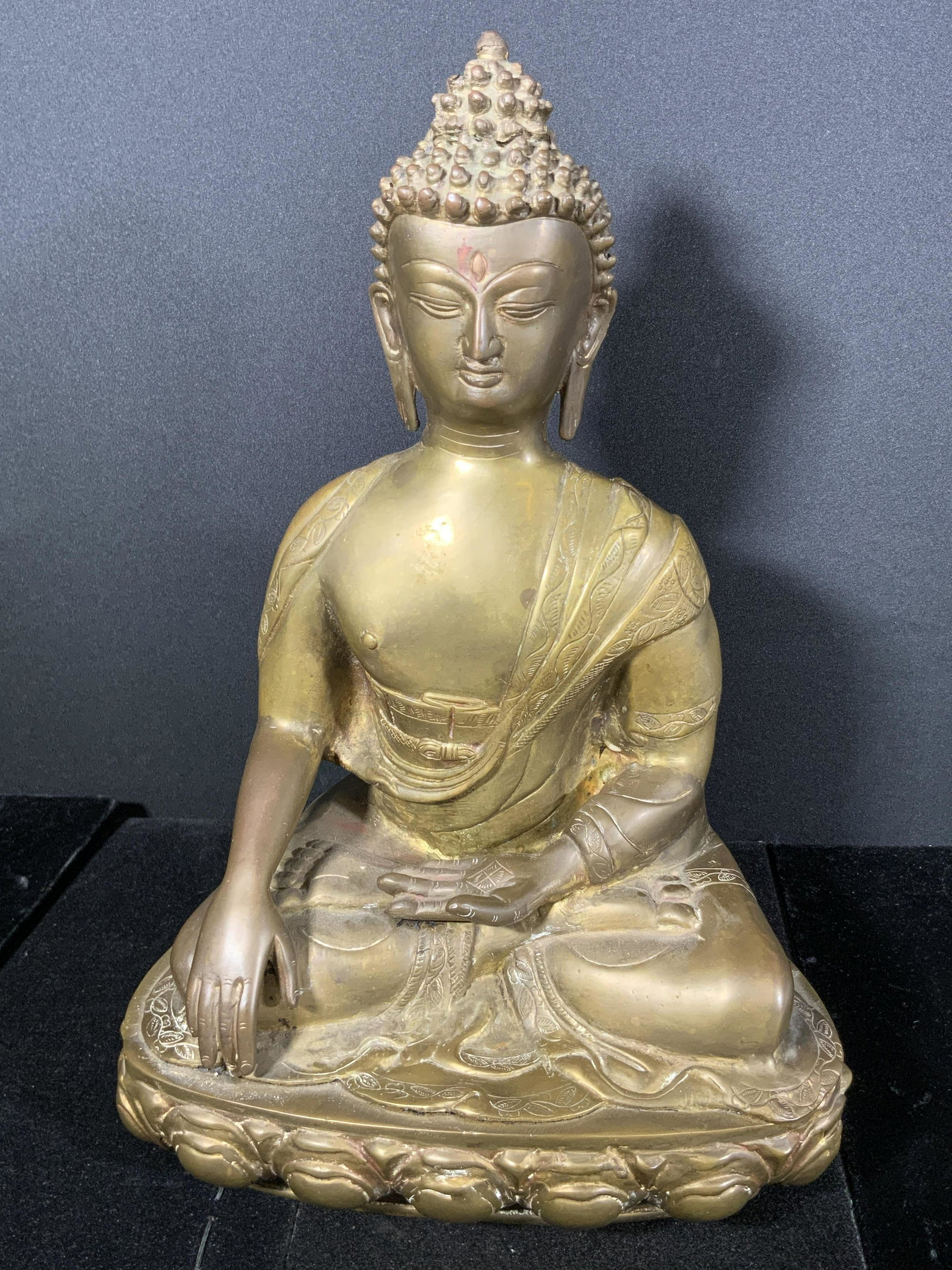 Painted & Etched Metal Seated Buddha Sculpture: A brass hued painted and etched metal Buddha sculpture. Buddha is depicted seated with one palm turned upwards in his lap. Measures approx 15H x 10W in. Some surface wear and wear to paint. Piece is w