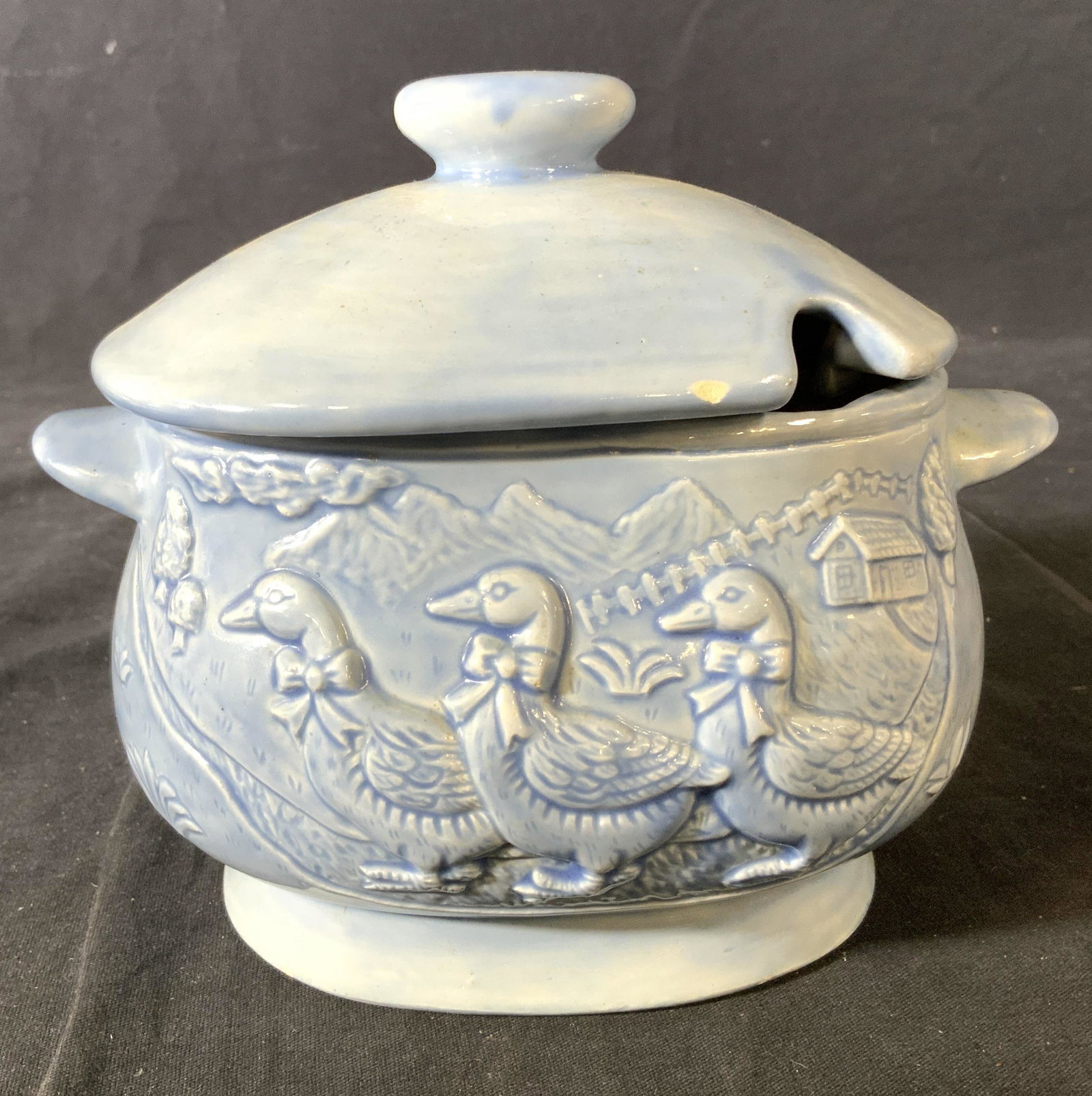 Vintage Signed Porcelain Gravy Boat W Lid: Underside is signed RA 12-87. Piece is light blue toned. Dish has handle of each side and includes lid. Piece also has beveled Duck figure detail. Piece measures approx 7 inches long 5 inches deep 6 i