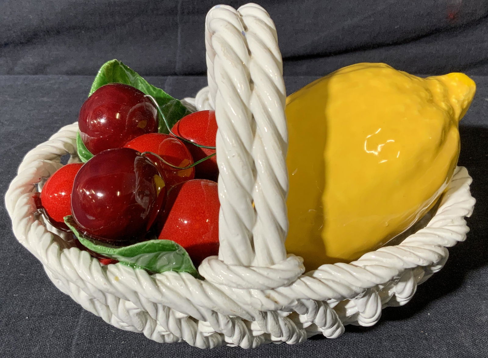 Ceramic Lemon and Cherries in Basket: Ceramic Lemon and Cherries in Basket, marking to underside illegible, subject a yellow ceramic lemon and red ceramic cherries in a white ceramic basket, measures 5 x 7 x 4 1/2 inches, surface wear to