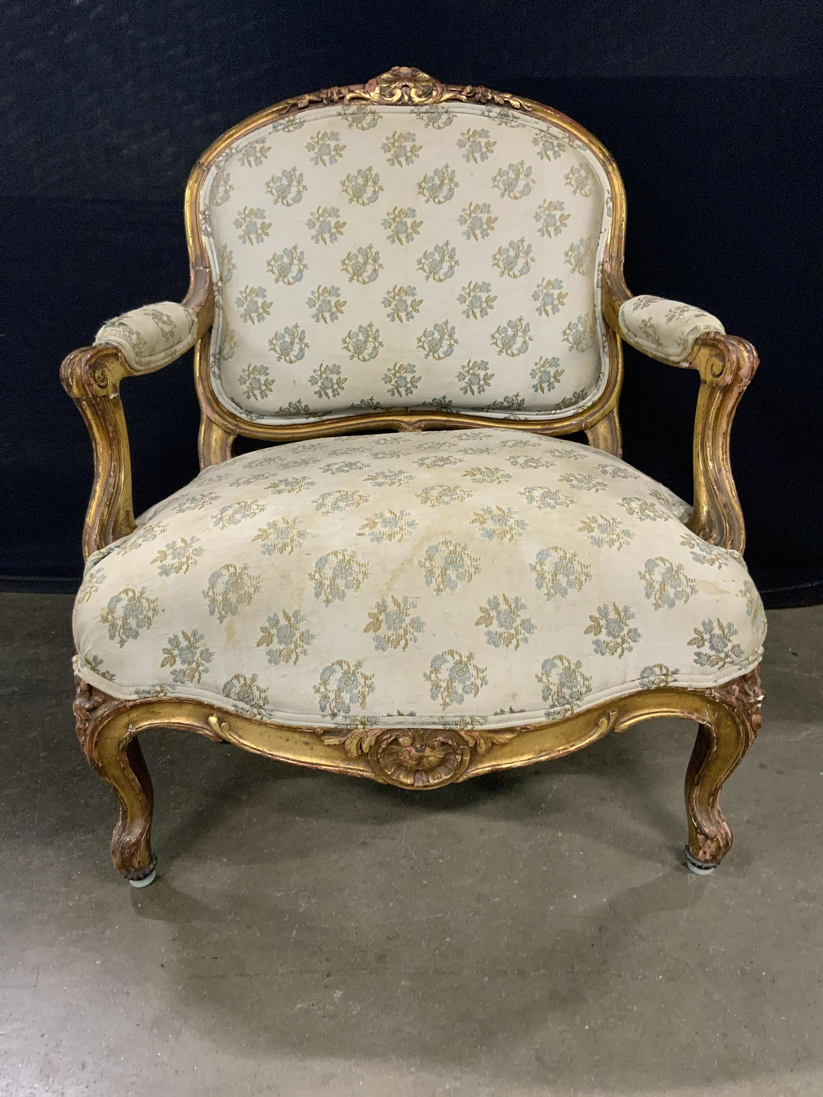 Louis XV Antique Low Bergere: Bergere has Louis XV style. Piece has gold leaf chair frame. Chair has multi toned floral & leaf detailed upholstery. Edges of upholstery have double welting. Piece measures approx 29 inches tall 25 i