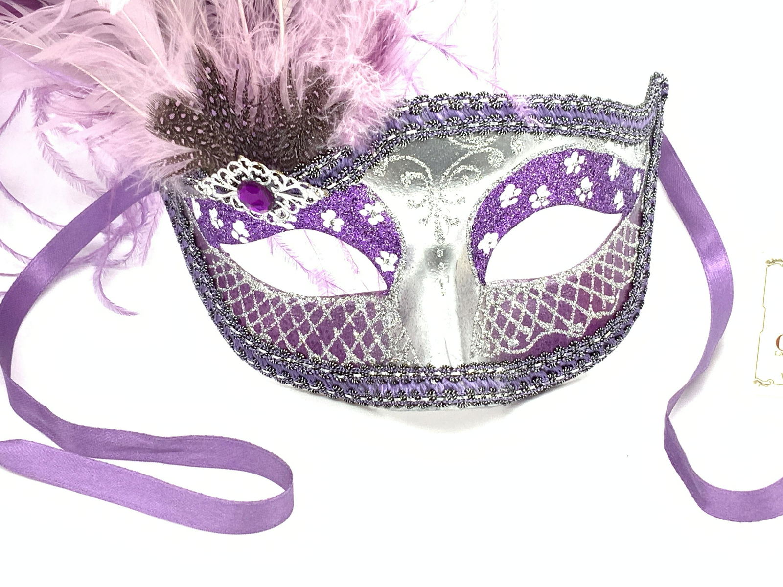 Venetian Feather Carnevale Mask w Org Tag: Hand painted by Venetian artists, hand made using Papier Machè, dyed purple feather plume, possibly ostrich feathers. Purple sateen ribbon to tie around head. Original tag attached, reads ‘Carta Al