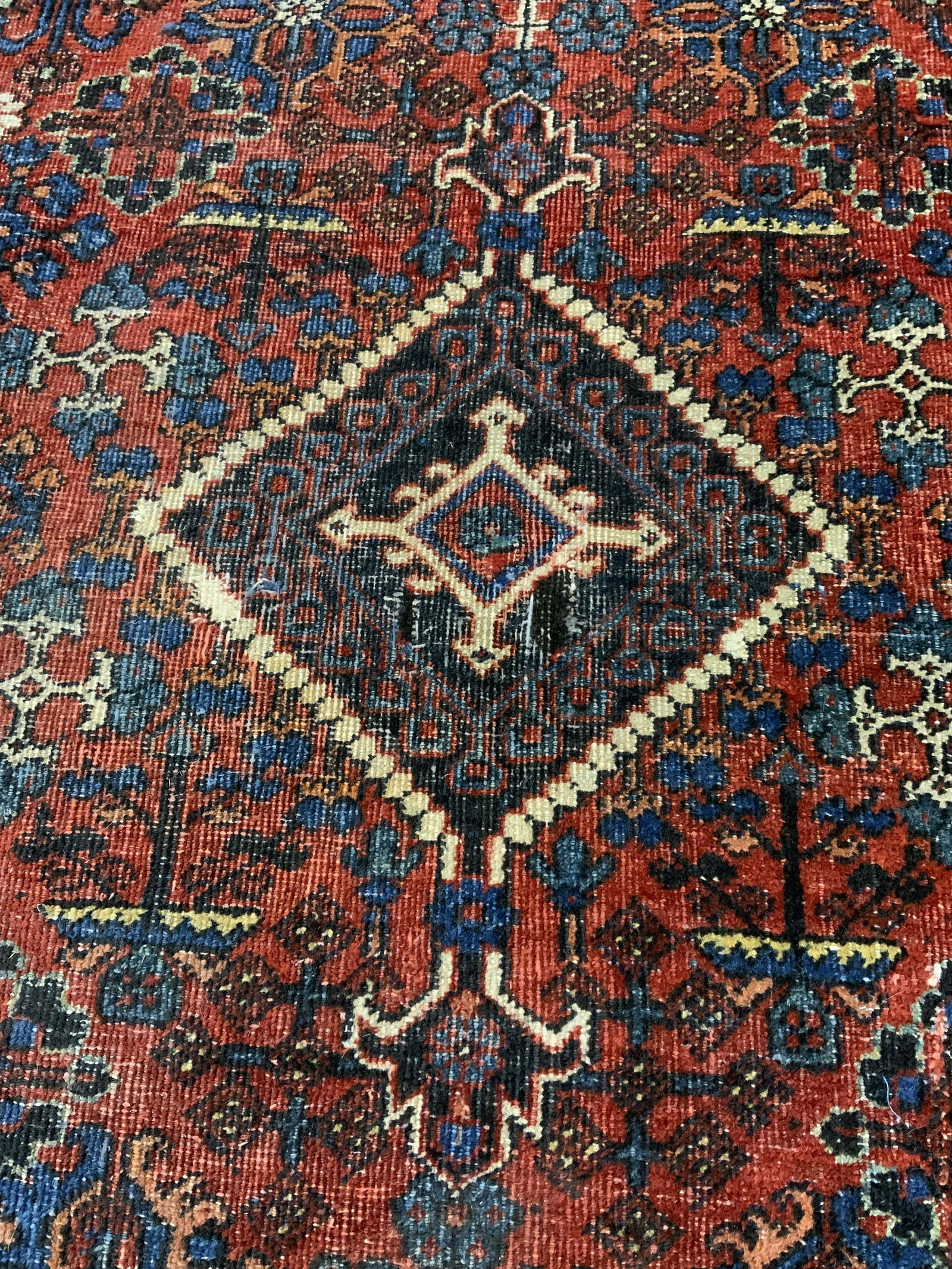 Vintage Persian Area Rug: Vintage Persian rug. Sides are weighed down with leather strips. Decorated with multi toned floral and geometric patterns. Ends appear to have been fringed. Wear is consistent with age and use. Measur
