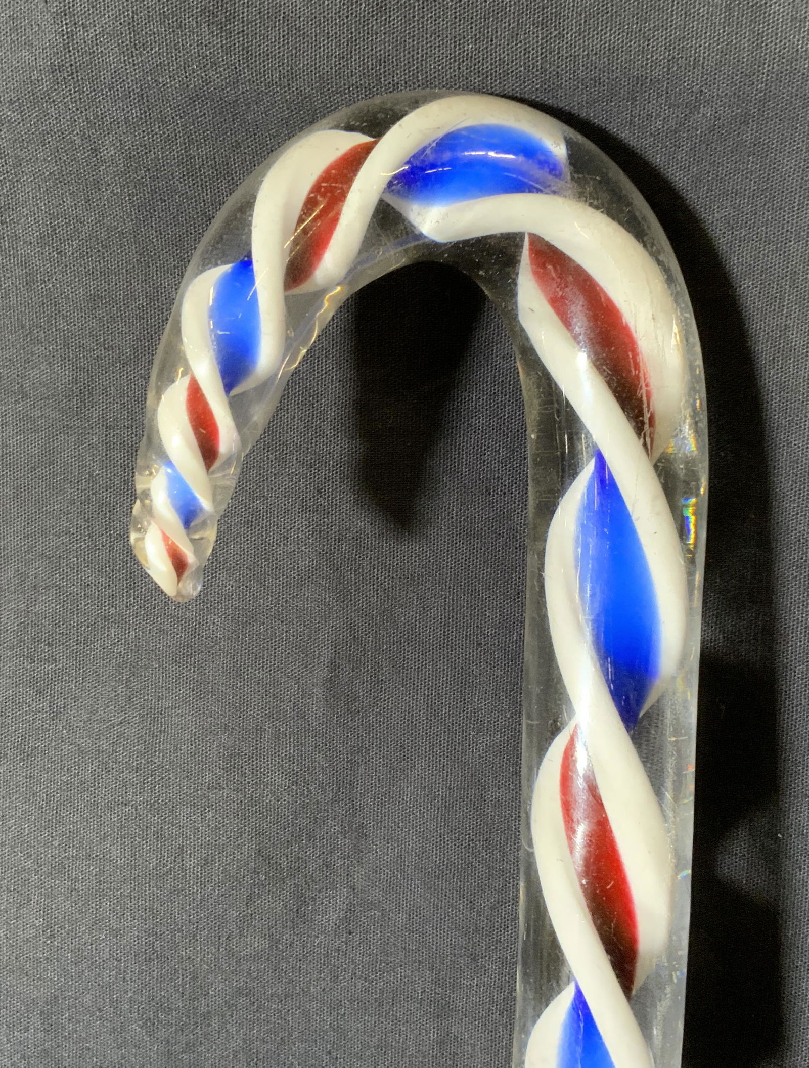 Art Glass Walking Stick: Art glass walking stick. Decorated with red, white, and blue enamel strips, enamel and handle are spiraled. Wear is consistent with age and use, chipping to bottom of cane. Measures approx 41 inches h