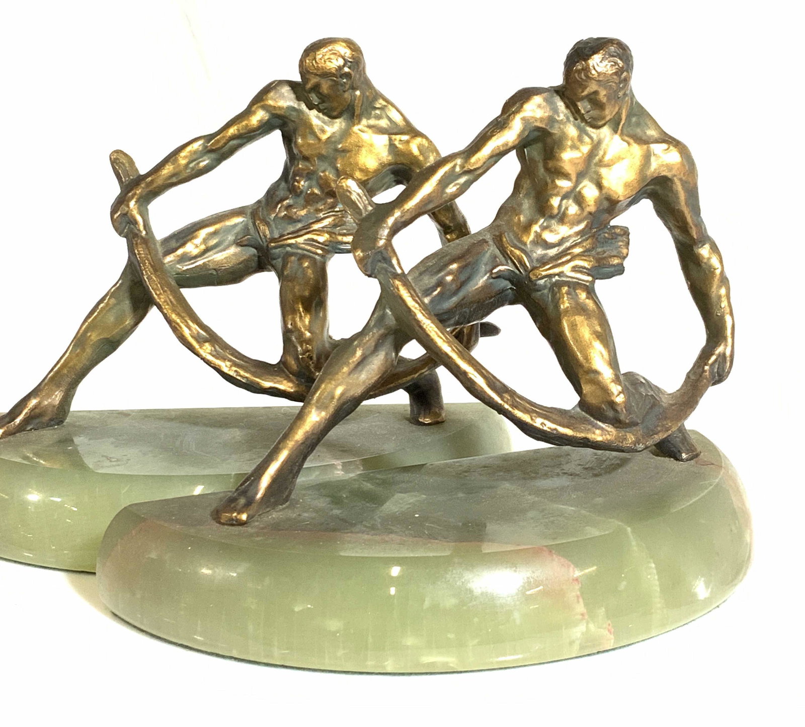 Gilt Bronze Olympian God Sculpture Bookends, 2: 2 Eccentric Pair of Gilt bronze partially nude sculpted man bending metal. Sculpture sits atop natural green stone demilune base. Velvet undersides. Measures 7.5 x 3.5 in. Ht 5 in. Gilt bronze bookend