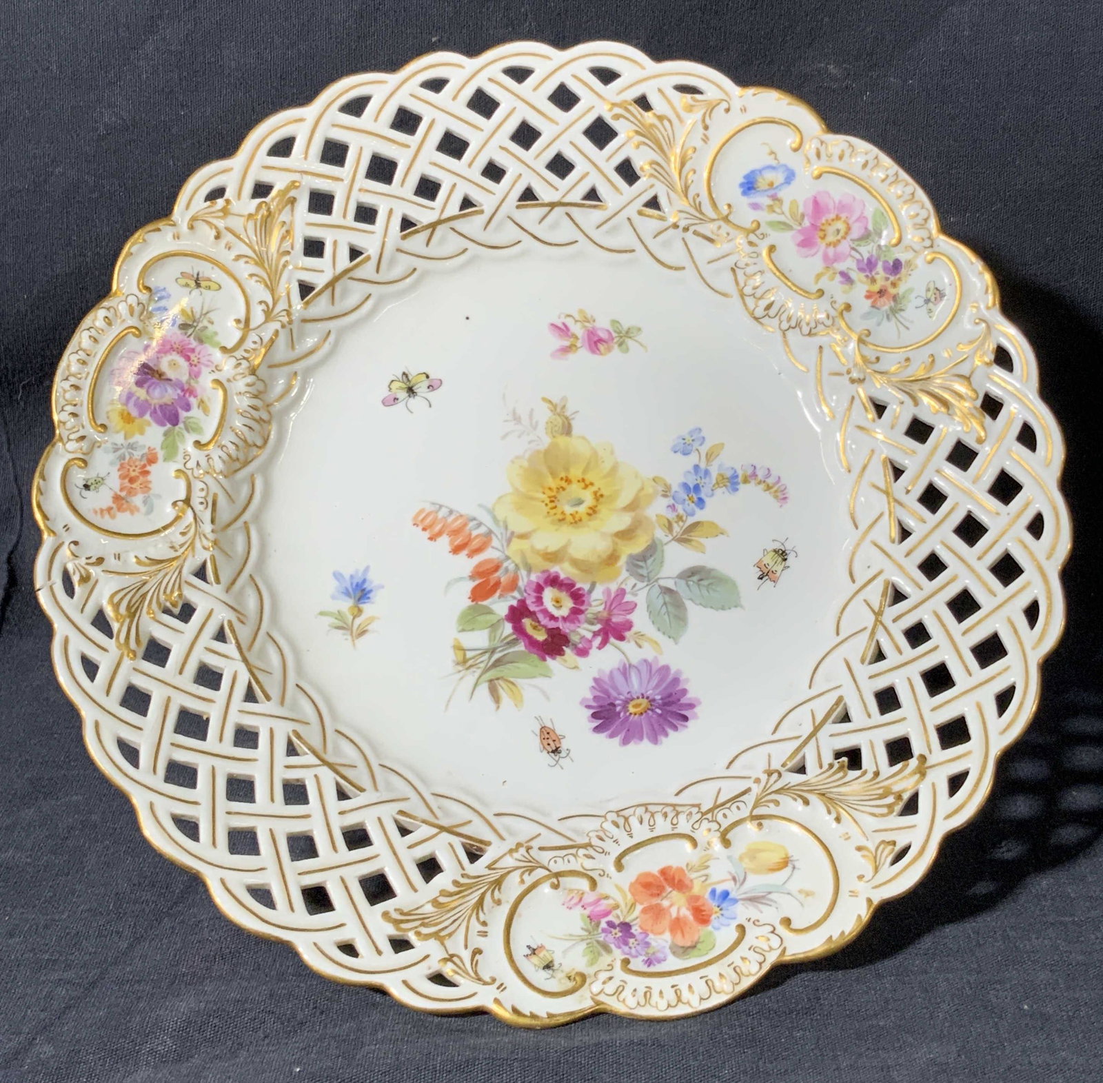 MEISSEN Signed Floral Porcelain Pedestal Plate: A white porcelain pedestal plate with lattice edges and hand painted designs throughout the obverse and reverse. Florals along the center and rims, gilt line work throughout. Underside trademarked wit