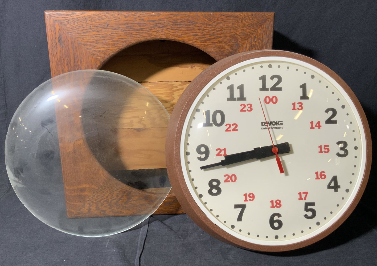 Vintage DEVOKE DATA PRODUCTS Wall Clock: A wall clock crafted by DEVOKE Data Products. White clock face with red and black numbers. Exterior is brown hued. Crafted from glass and composite materials. Underside possesses sticker, reads APR 4 