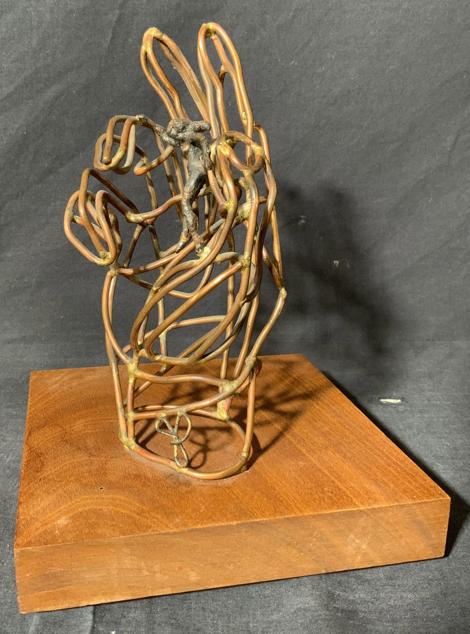 Woman Climbing Peace Sign Copper Wire Sculpture: Woman Climbing Peace Sign Copper Wire Sculpture, no apparent hallmarks to piece, shows a woman holding onto the ring finger as she looks down, measures 7 w x 7 l x 9 3/8 h inches, wear consistent with
