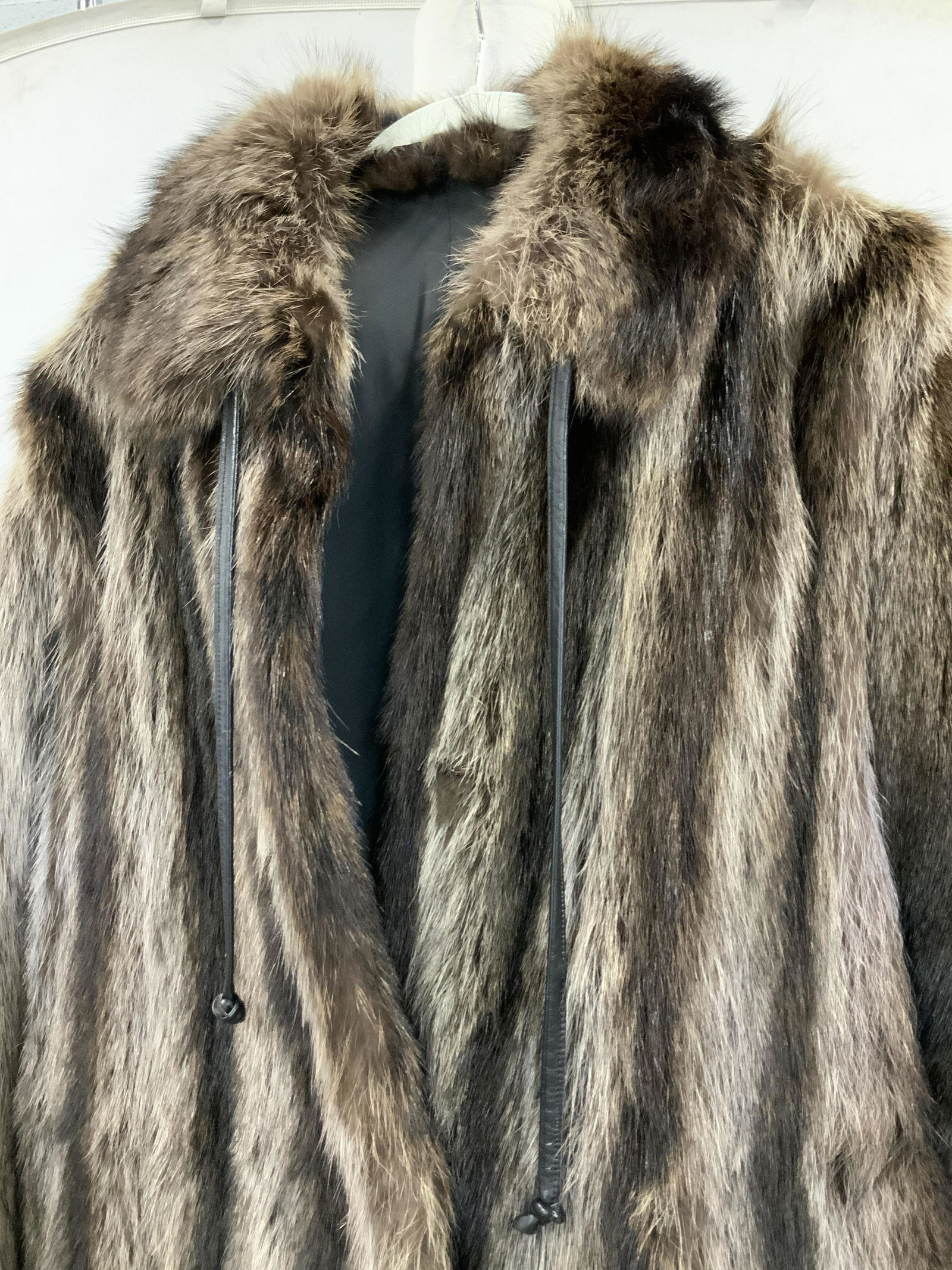 Raccoon Long Length Fur Coat: Well made raccoon fur coat, silvery grey and ash brown fur, long length 47 in., black silk lining with inner waist tie belt, no hemming issues, leather pull strap to tighten shawl collar. Fur is thick