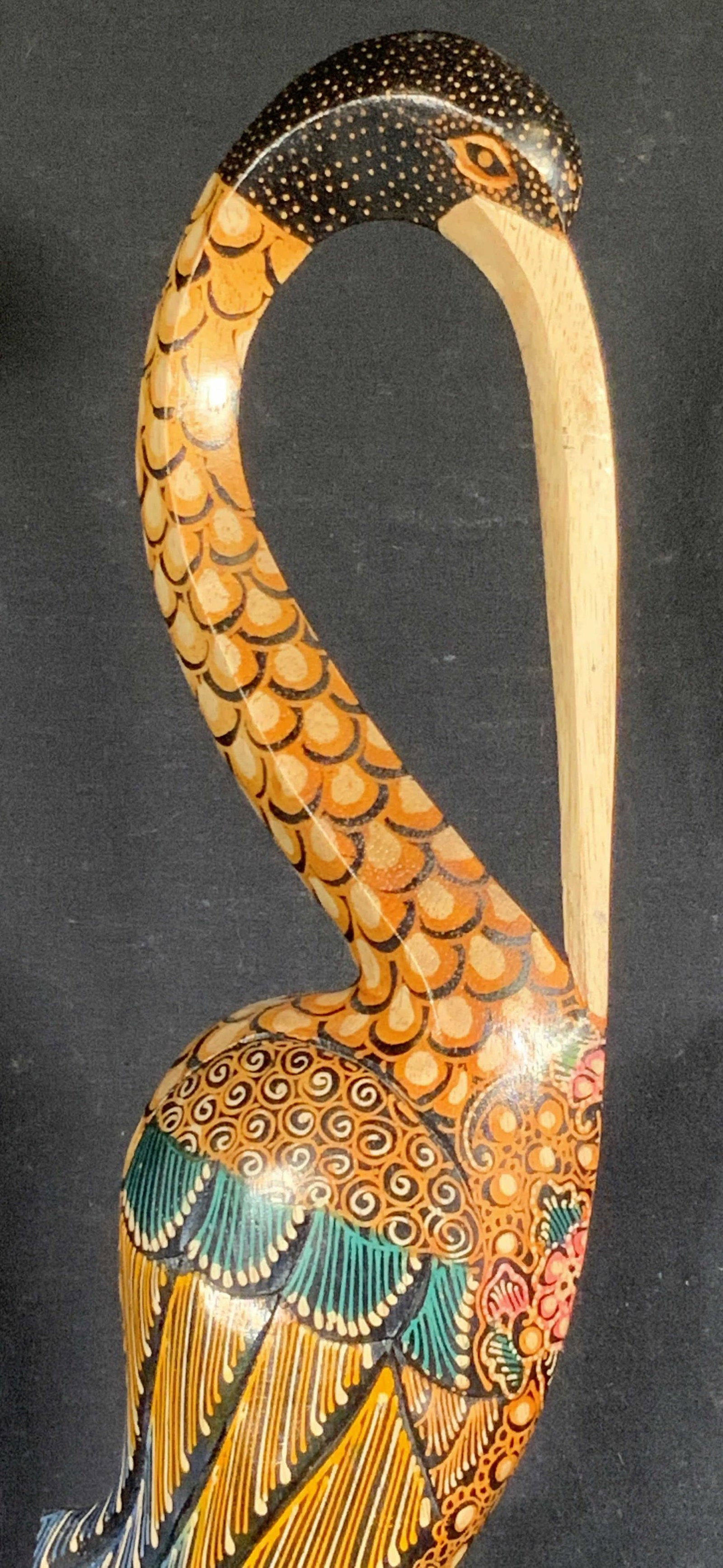 Floor Sized Hand Painted Wooden Crane Statuette: A hand painted wooden crane statuette crafted from wood. Piece measures approx. 31H x 6W in. Primarily black hued with yellow, blue, and pink tones. Underside possesses felt style material. Piece has 
