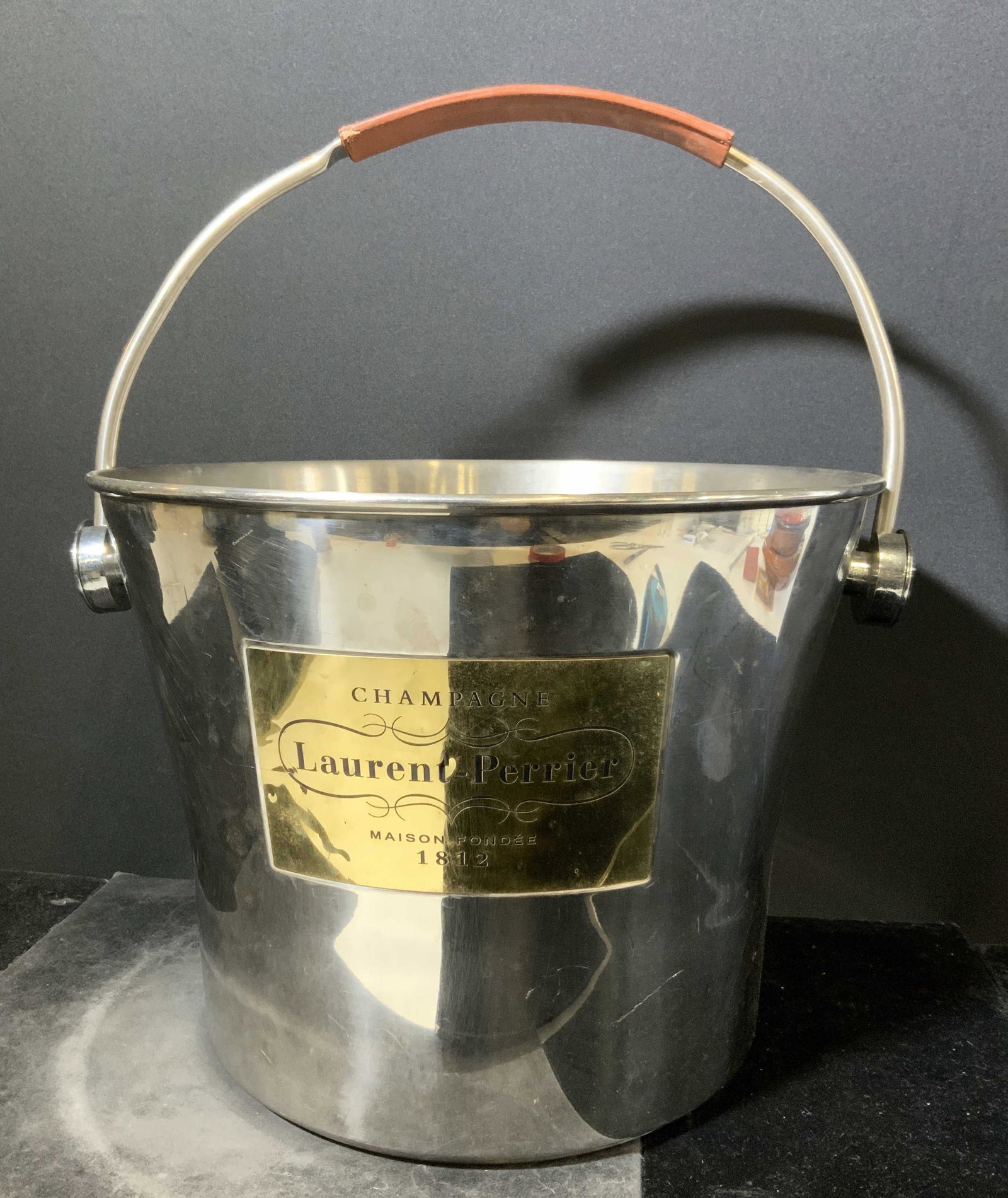 LAURENT PERRIER Champagne Bucket: LAURENT PERRIER Champagne Bucket. Oversized champagne bucket, silver toned metal, leather style detail on handle, reads LAURENT PERRIER. Brass toned plate on front reads Champagne LAURENT PERRIER Mais