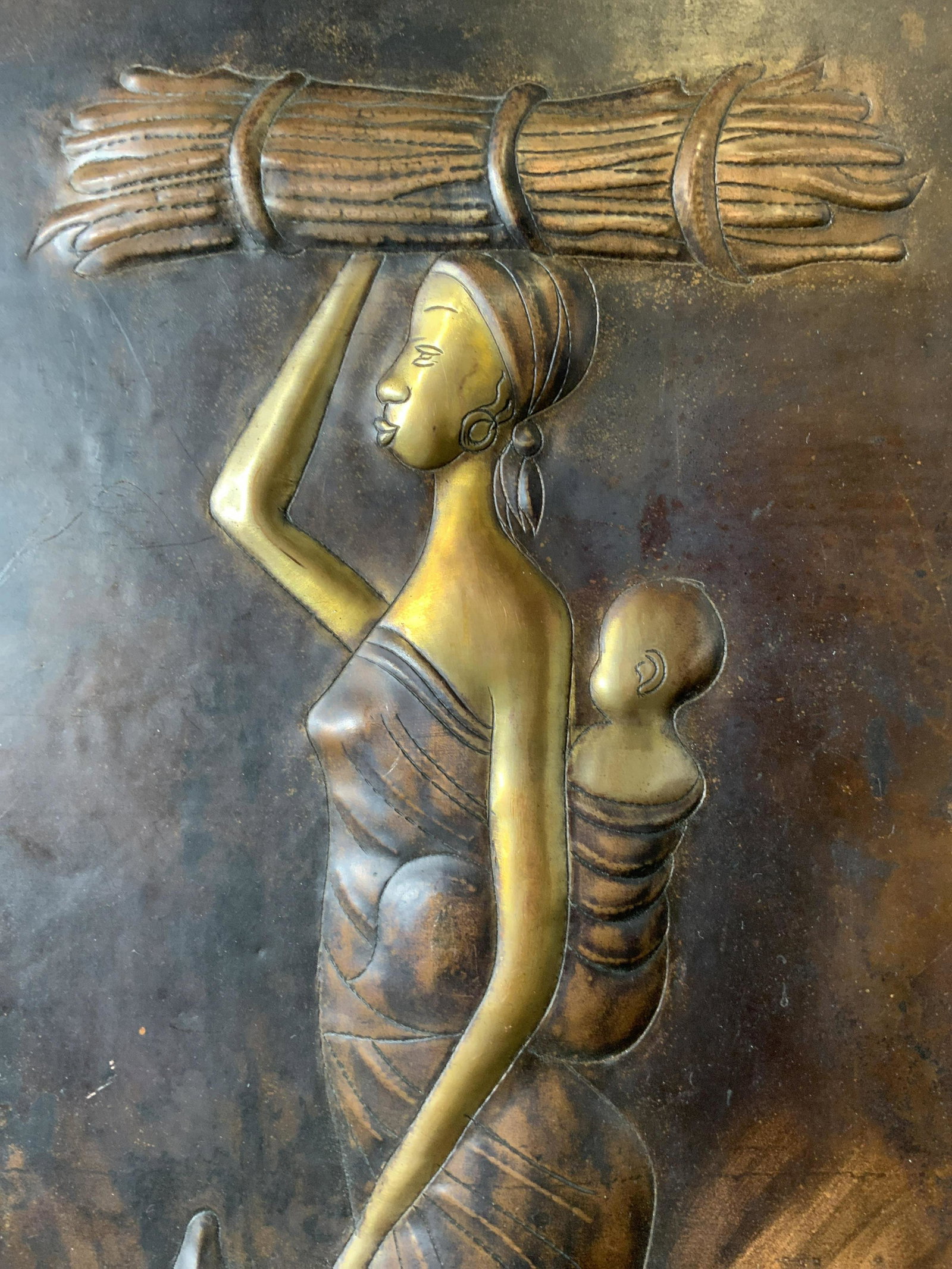Signed Mother and Child in Field Metalwork: Signed Mother and Child in Field Metalwork, likely brass, inscription to lower center is illegible, subject a woman in a field with her child strapped to her back, measures 12 x 20 inches, not framed,