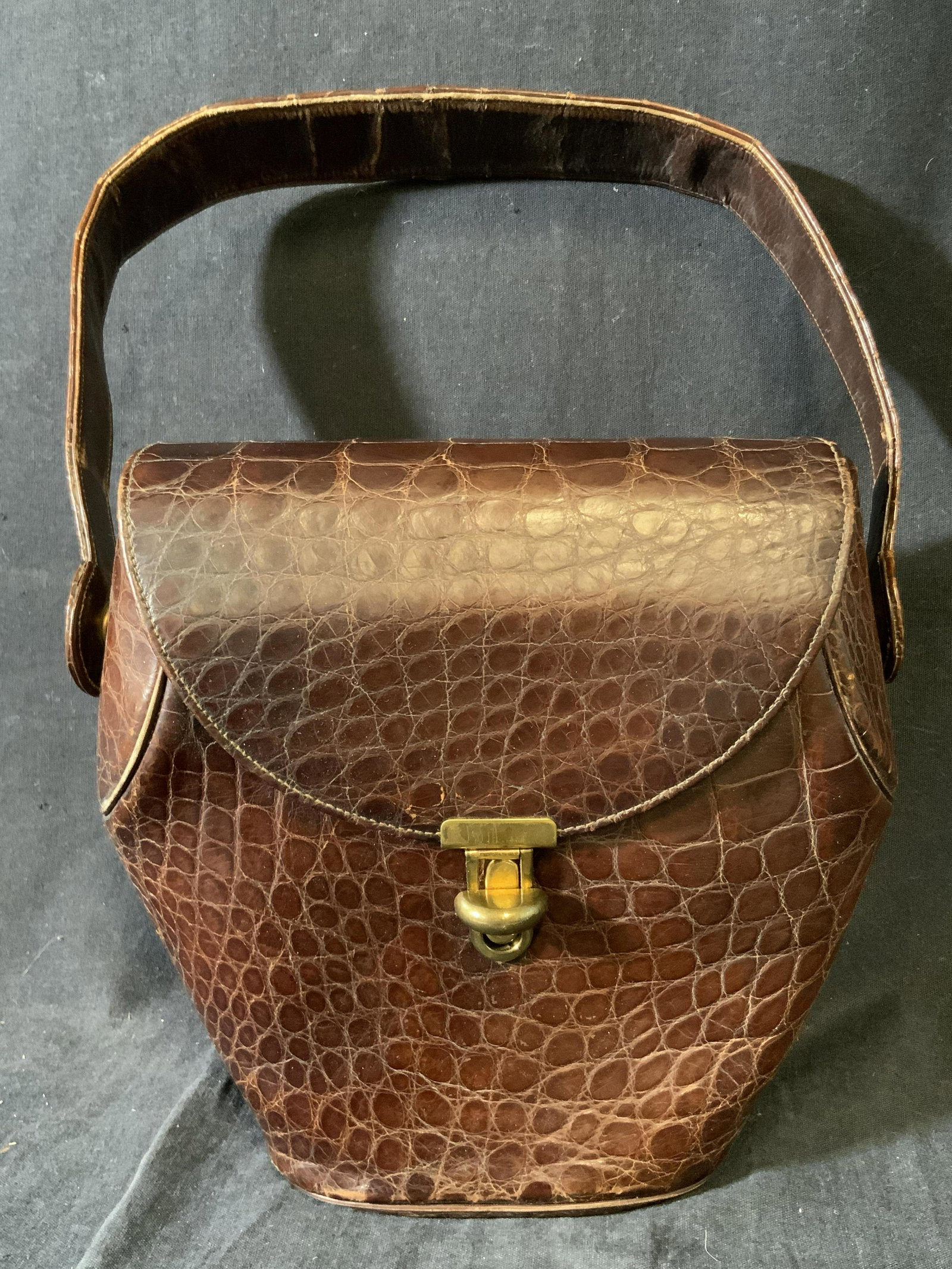 Vintage Brown Reptile Style Ladies Handbag: A vintage brown reptile leather style handbag. Piece features a top handle. Antiqued gold tone metal hardware. Interior is lined with a beige hued leather style material. Pockets to interior. Some dis