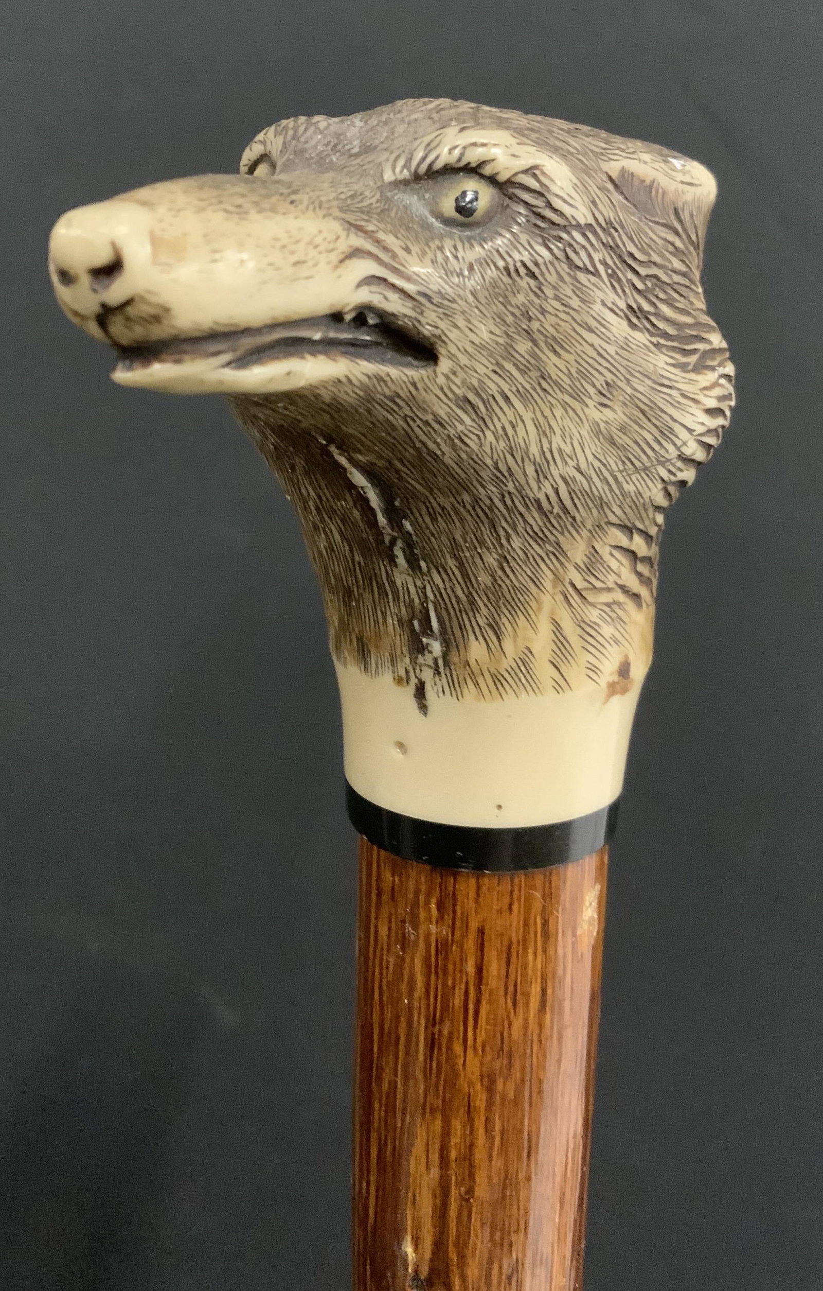Vintage Scrimshaw Wolf’s Head Walking Stick: Vintage walking stick. Handle is scrimshaw, possibly on resin. Resembles a wolf’s head. Shaft is wooden, walnut finish, metal ferrule. Wear is consistent with age and use, some chipping to wolf ears