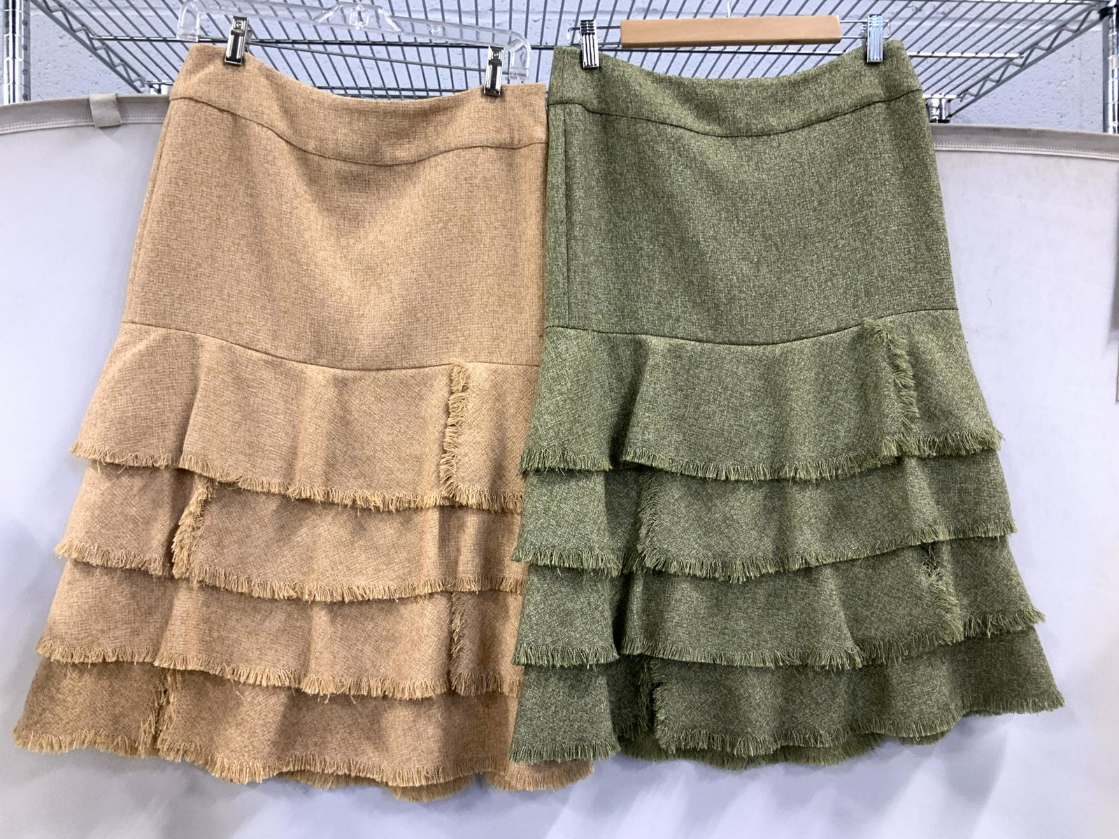 Lot 2 H&M Contemporary Dress Skirts: Identical Fabric Skirts with lining, both size 8, backside zipper and large fabric cover3d button. One in moss green, the other in wheat. Layered skirt, 27 in. Long. Both with labeled Designer H& M. P