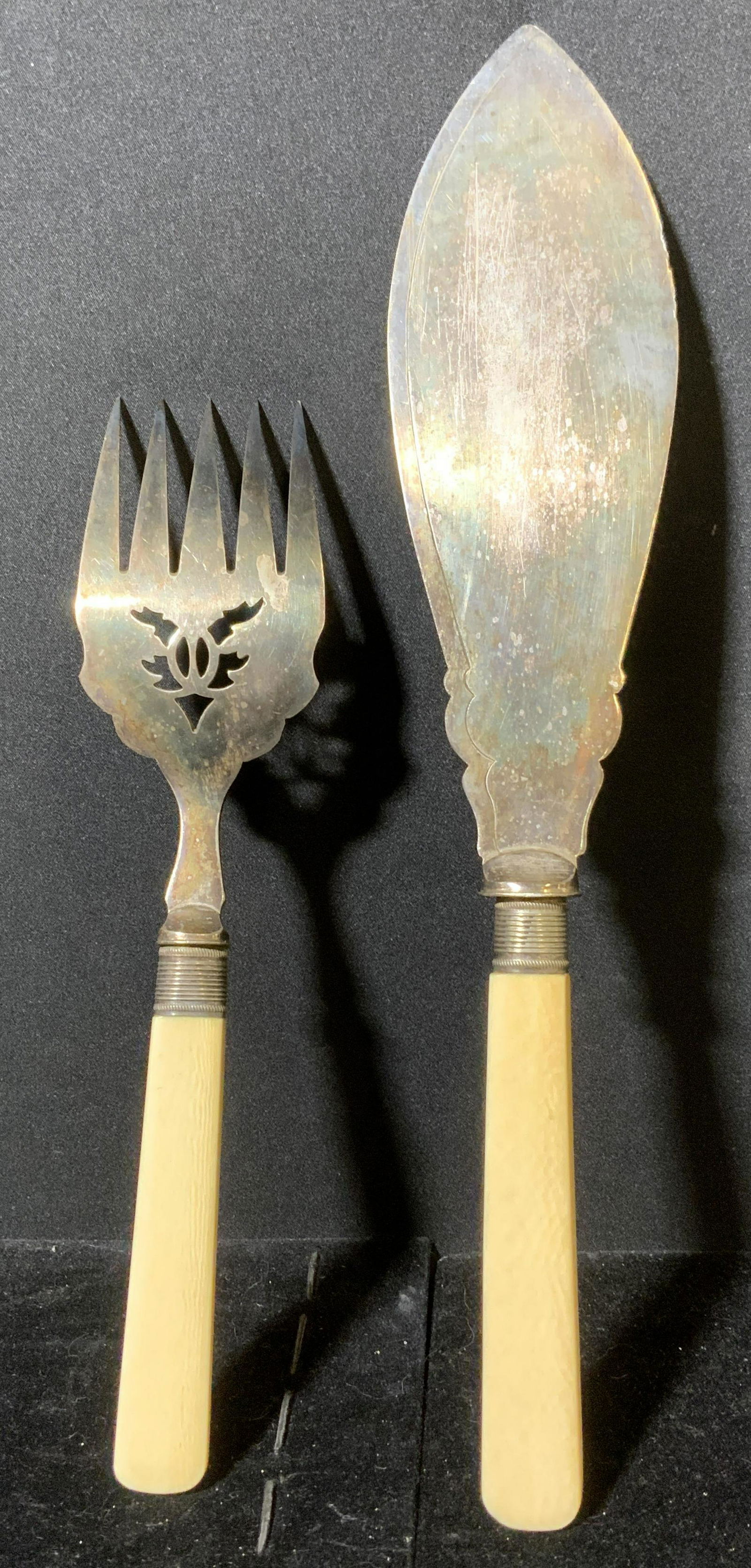 Lot 2 Vintage Etched Serving Utensils: Lot 2 serving utensils. Includes a fish knife and fish fork. Decorated with etched detailing, handles appear to be resin, possibly bone. Wear is consistent with age and use. Appear to be SILVERPLATED.