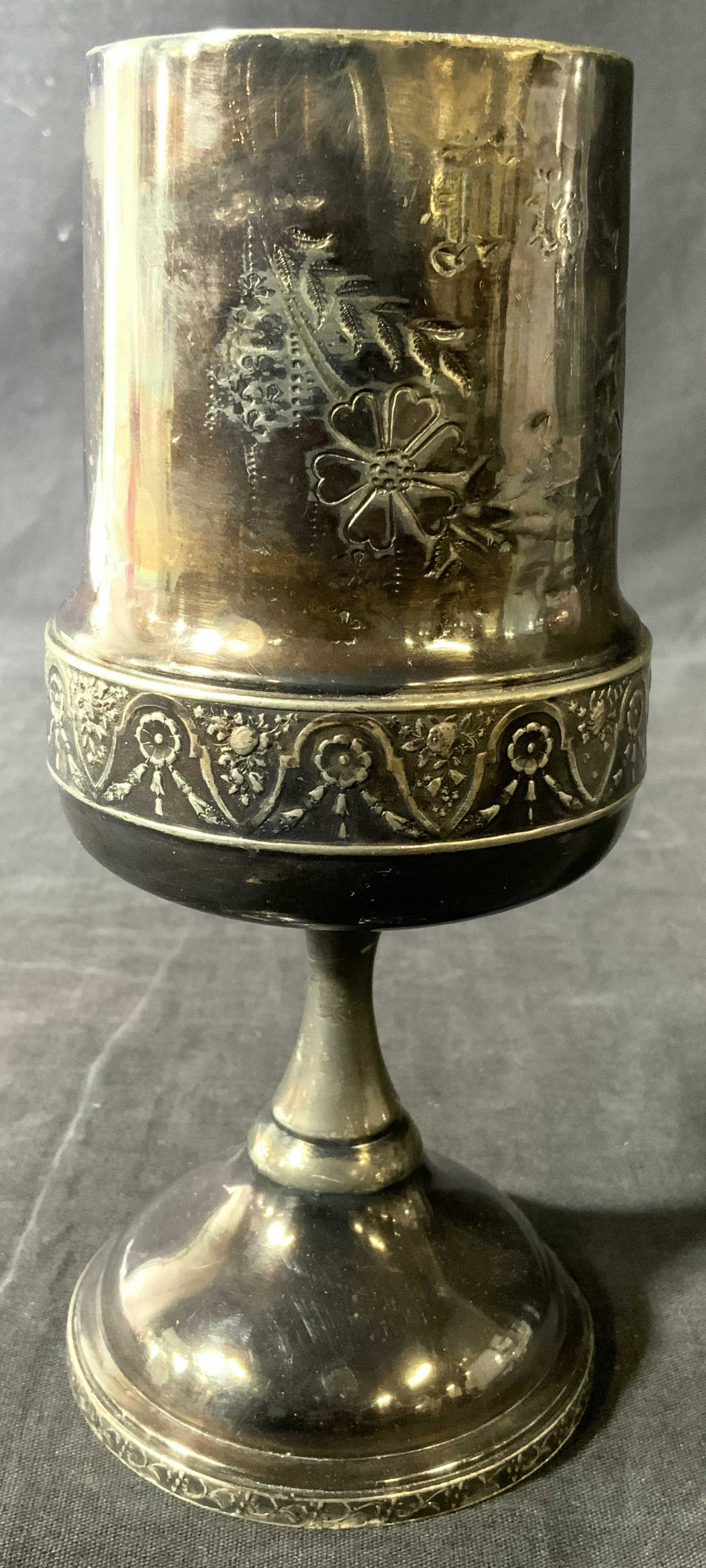 MERIDEN Silver Plate Quadruple Plated Chalice: Underside is inscribed MERIDEN SILVER PLATE CO QUADRUPLE PLATE. Chalice has dark silver tone with floral and leaf relief detail. Base is circular. Piece measures approx 7.5 inches tall 3.25 inches wid