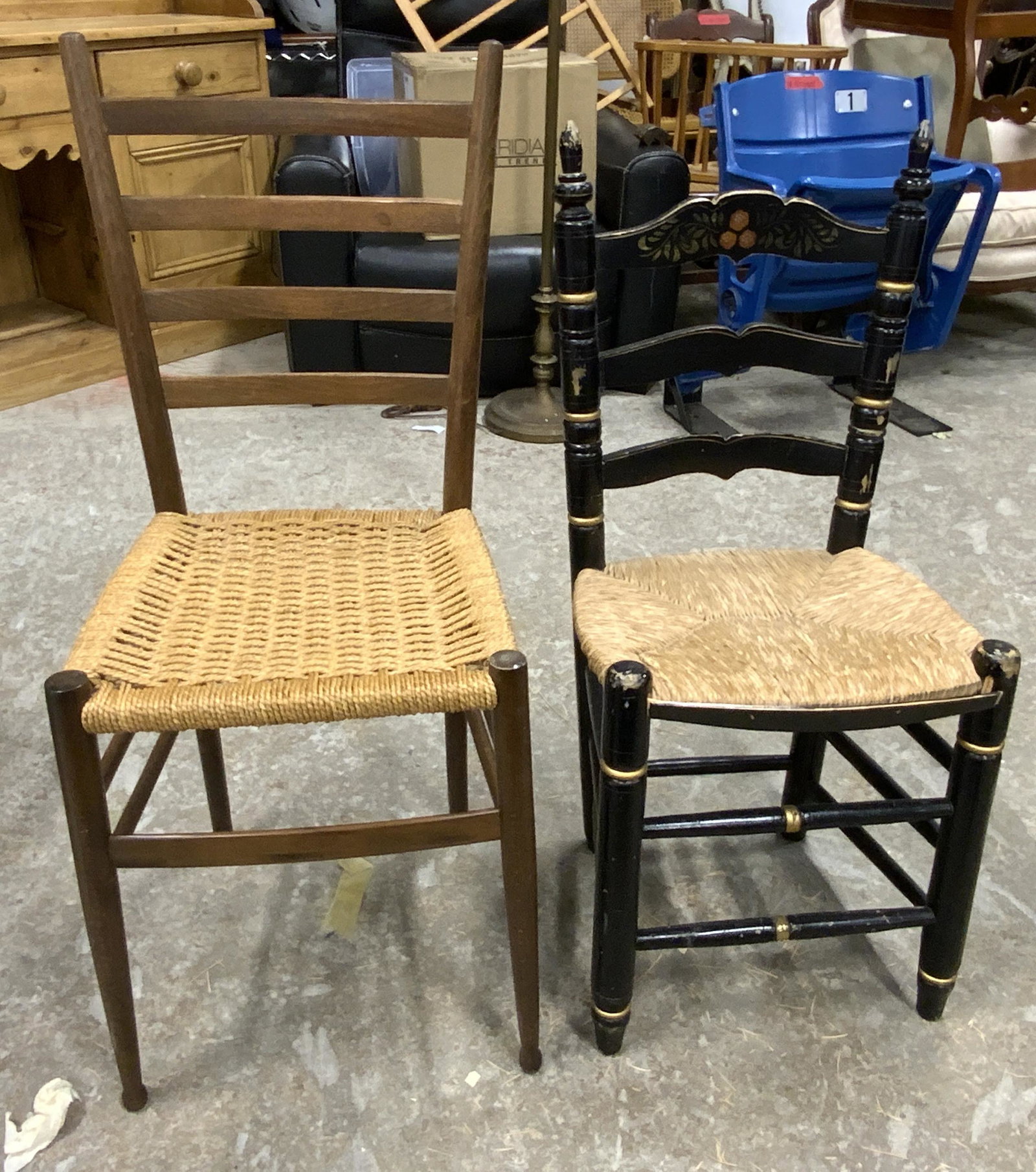 Lot 2 Vintage Wooden Side Chairs: Side chairs are vintage and wooden. Each piece has rush woven seating. One chair is black, while the other is brown toned. Each piece has box shaped stretchers in between legs. Largest measures approx