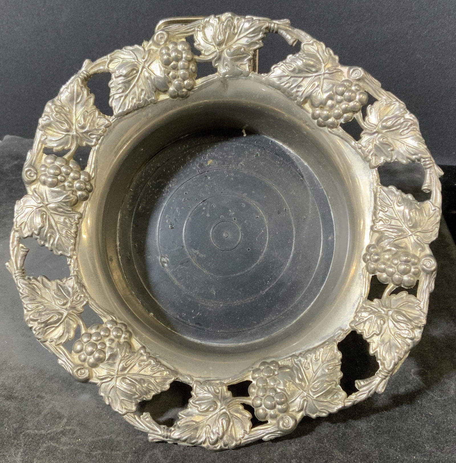 GODINGER Silver Plated Wine Coaster: Silver plated wine coaster. Cast grape and vine-like detailing decorate the rim. Center is composite, possibly plastic, decorated with carved concentric circles. Wear is consistent with age and use. M