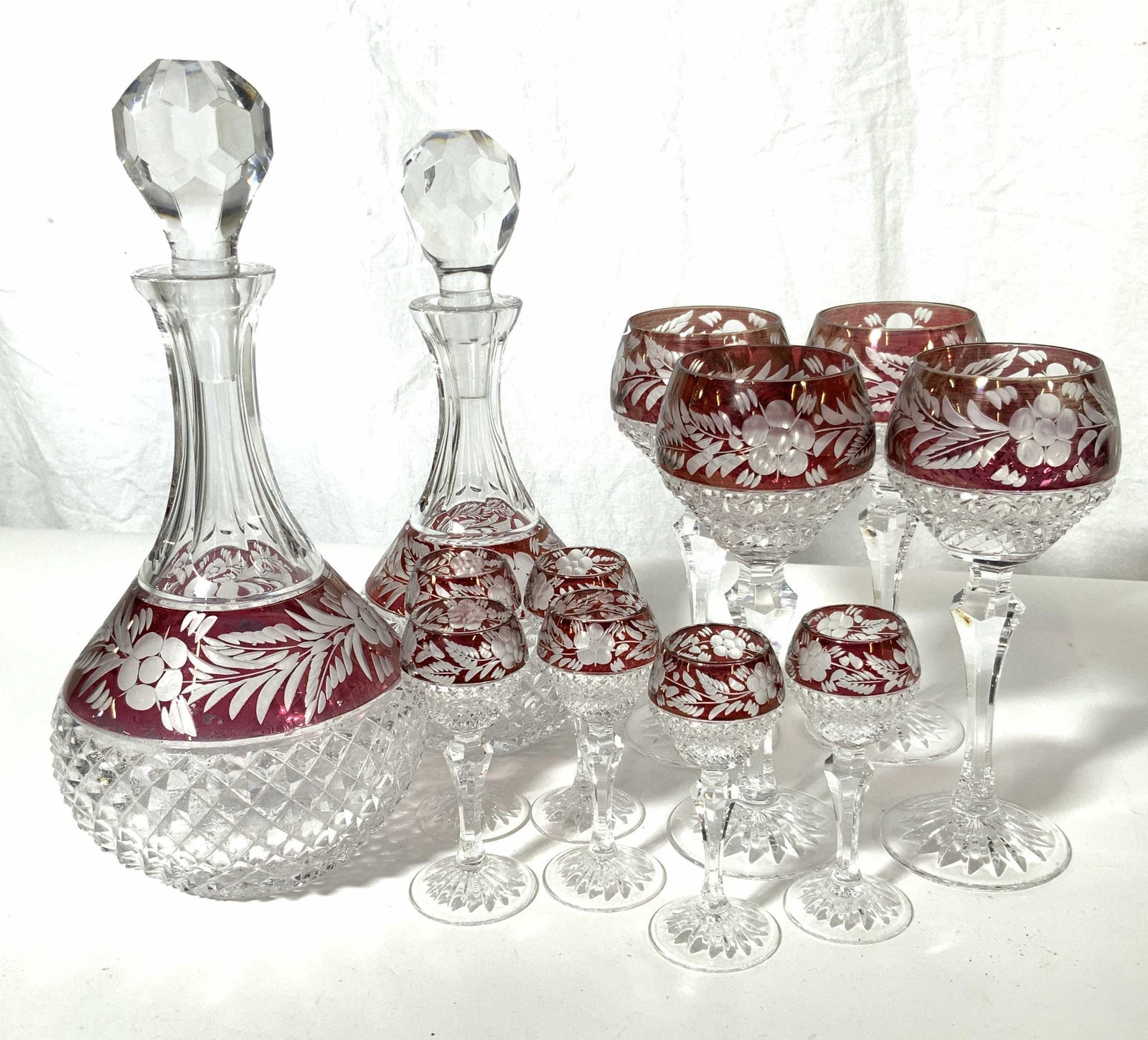 Cut Bohemian Glass Decanters & Stemware Set: Cut glass stemware set, includes 2 decanters, 4 wine goblets and 6 cordials all with Cranberry glass banding, heavy cut flower pattern and floral detailing, tallest measures at approx 12 in. Glassware