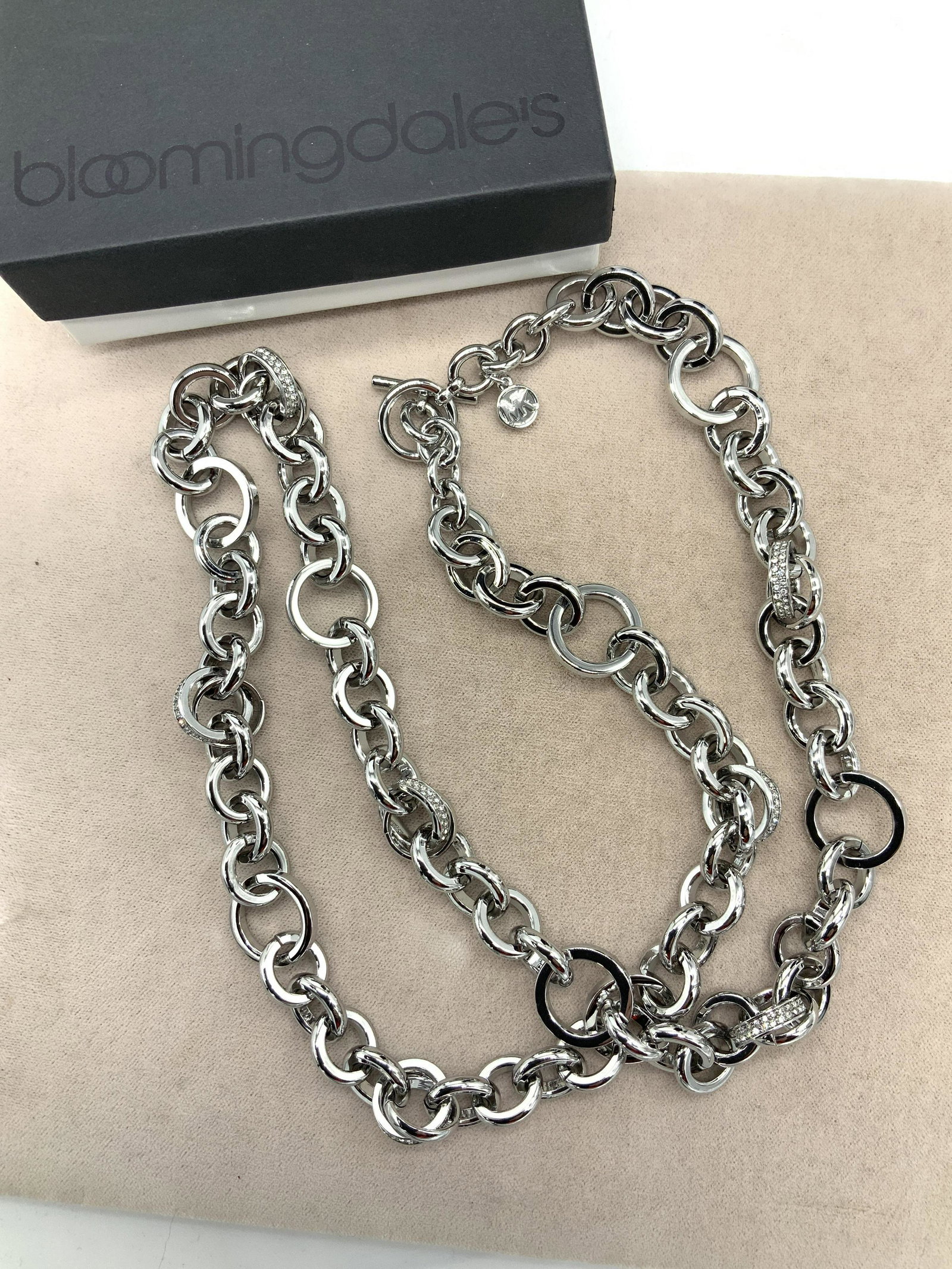 MICHAEL KORS Signed Gunmetal Link Chain Necklace: Hallmarked MK on charm, 26 in. Michael Kors cable link chain in gunmetal with occasional crystal diamonté links and toggle clasp. Piece is weighted and comes in a Bloomingdale’s Jewelry Gift box. N