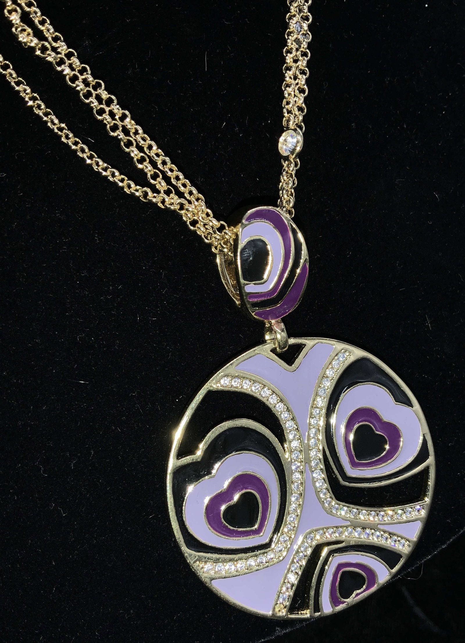 Bold Heart Enamel and Crystal Pendant Necklace: Adjustable choker necklace with bold large medallion pendant with heart motif. Violet, black and purple enamel set in polished gold tone metal. Double strand cable chain accented with clear crystal. P
