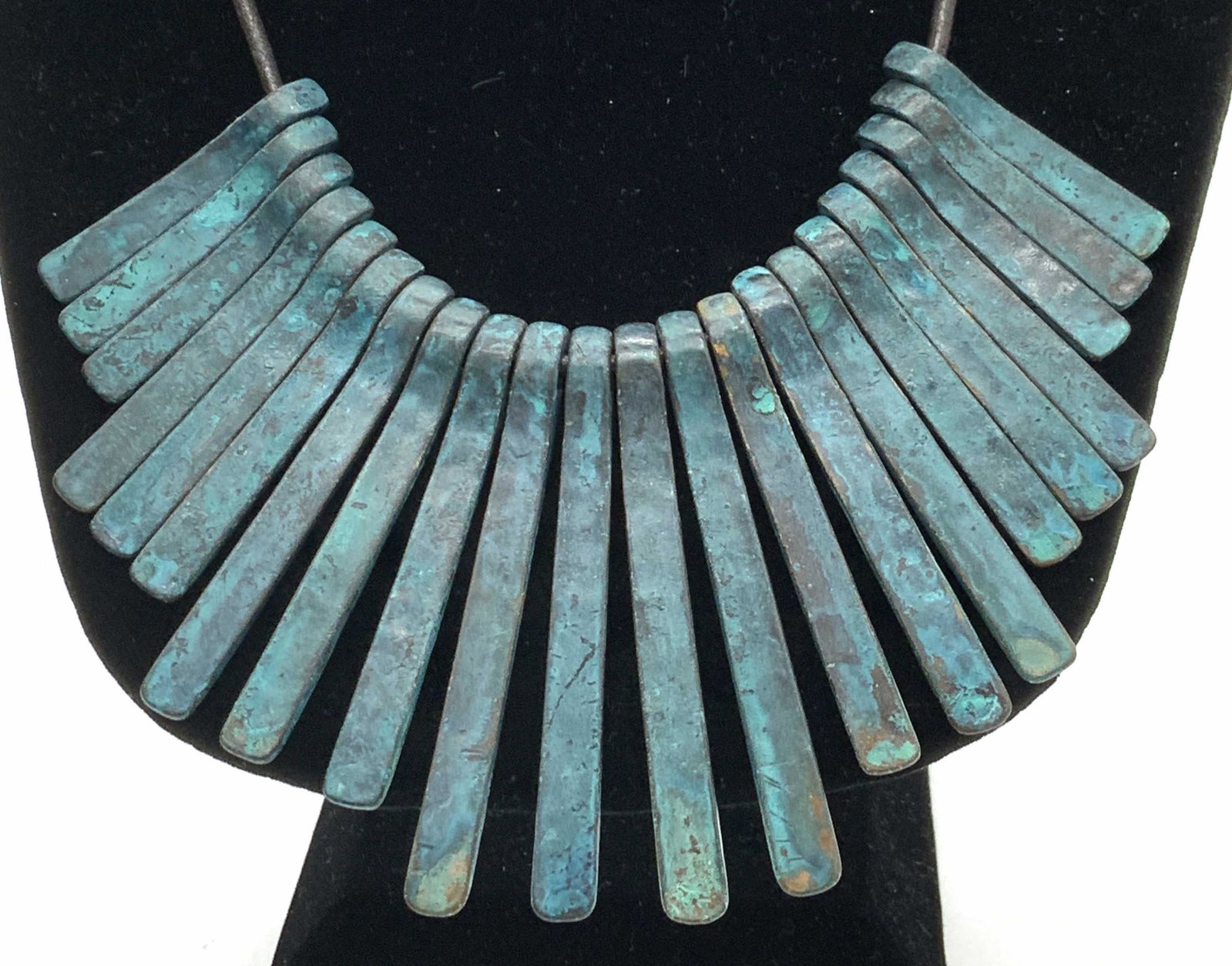 Kenneth COLE Industrial Bib Necklace on Cord: Adjustable necklace with lobster clasp, black cord, measures 16 in. longest. Tribal metal pendant painted in a green hue dangle from cord 2.5 in. All pendant shift off cord. Re purposed metal. signed 