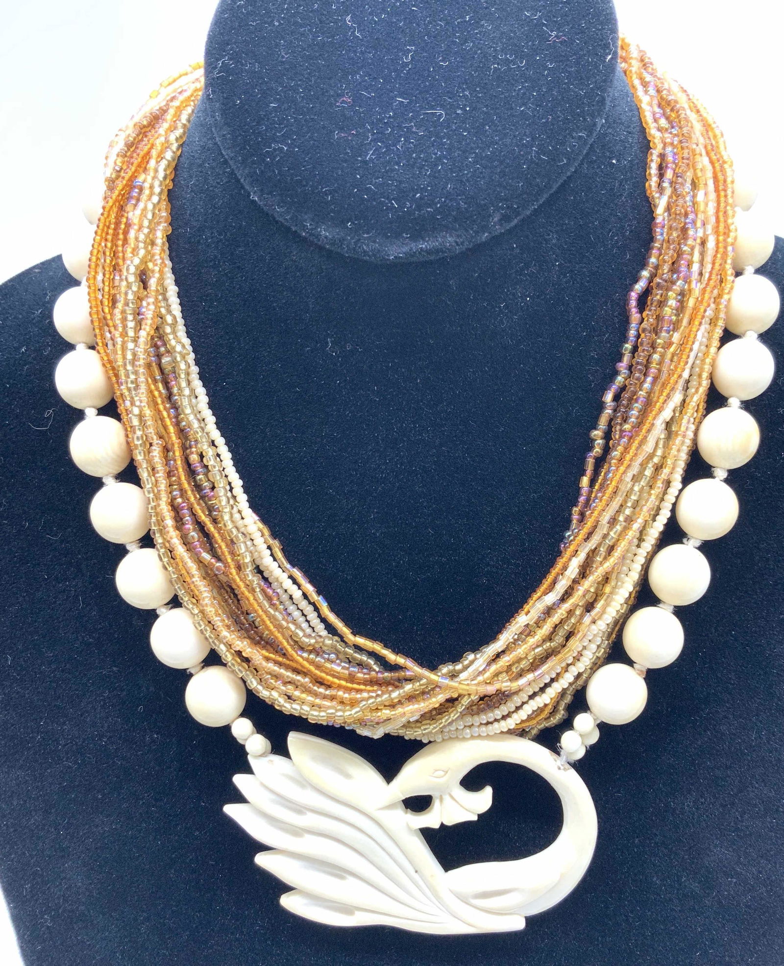 Lot 5 Vintage Jewelry, Bone Style, MOP: Lot 3 bangles, one made with Mother of Pearl on brass. MOP measures 1.25 in. Wide, 2 5/8 in. Diameter. Beaded multi strand necklace hand beaded with iridescent seed beads & golden tones, 14 in. L Swan