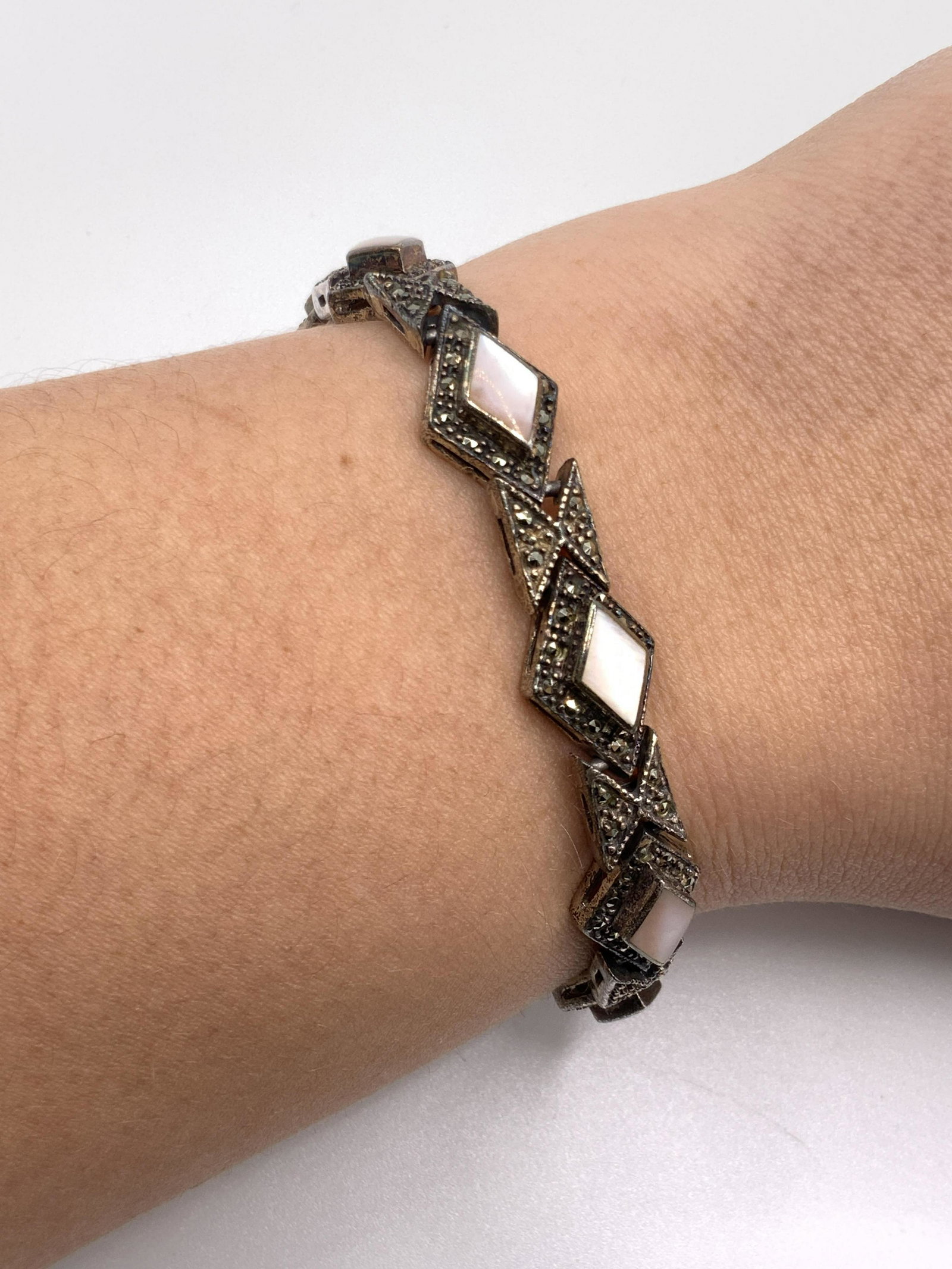 Vintage STERLING SILVER Mother of Pearl Bracelet: A vintage sterling silver bracelet with polished bezel set mother of pearl accents. Bracelet also features raised metalwork and marcasite. Box clasp closure. Marked on closure underside 925, MF. Brace