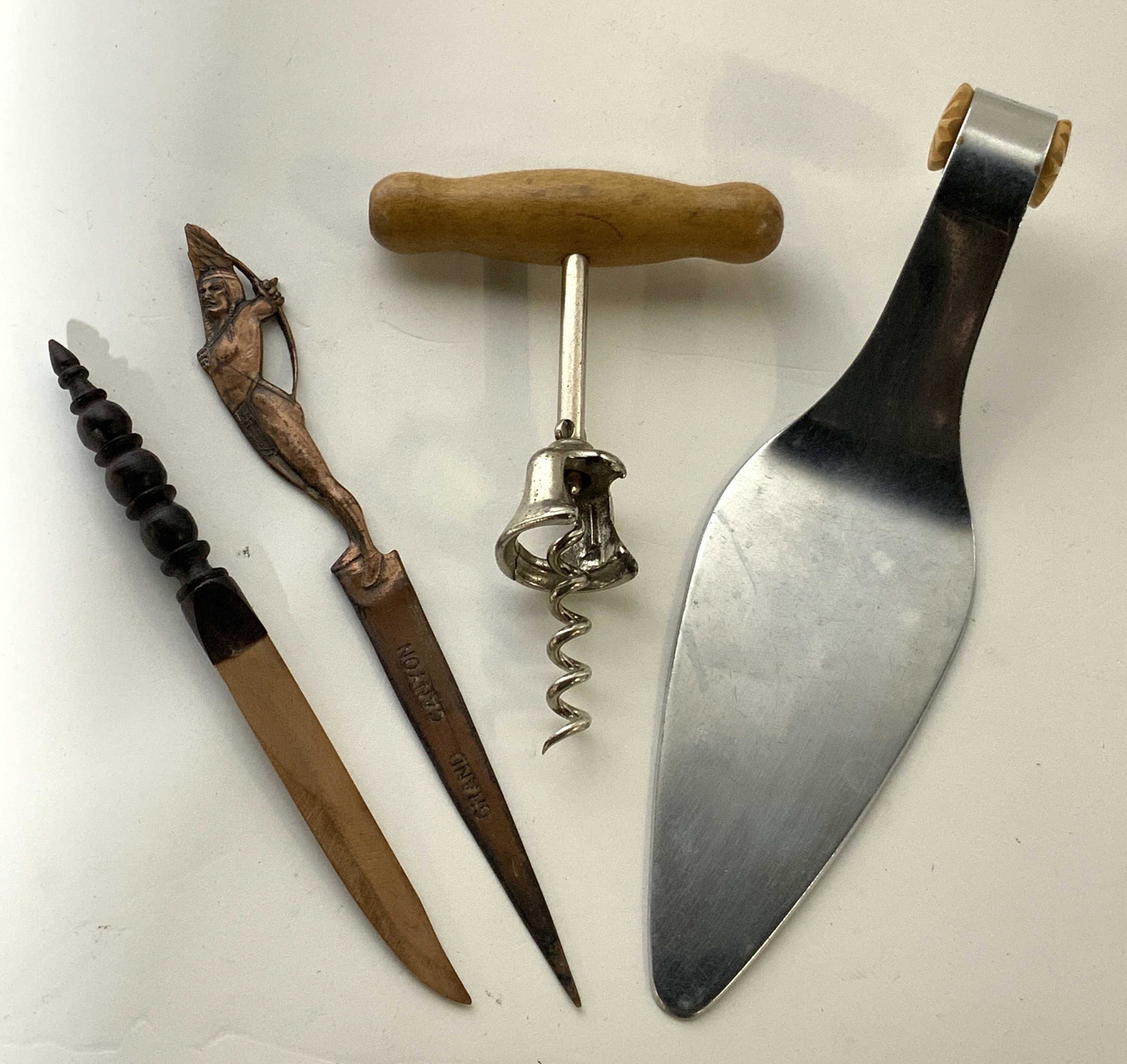 Group Lot 4 Kitchen & Office Accessories: A group made up of 2 letter openers, one wine bottle opener, and one cake knife. One letter opener is marked ‘Arizona Genuine Copper’ on one side and ‘Grand Canyon’ on the corresponding side a