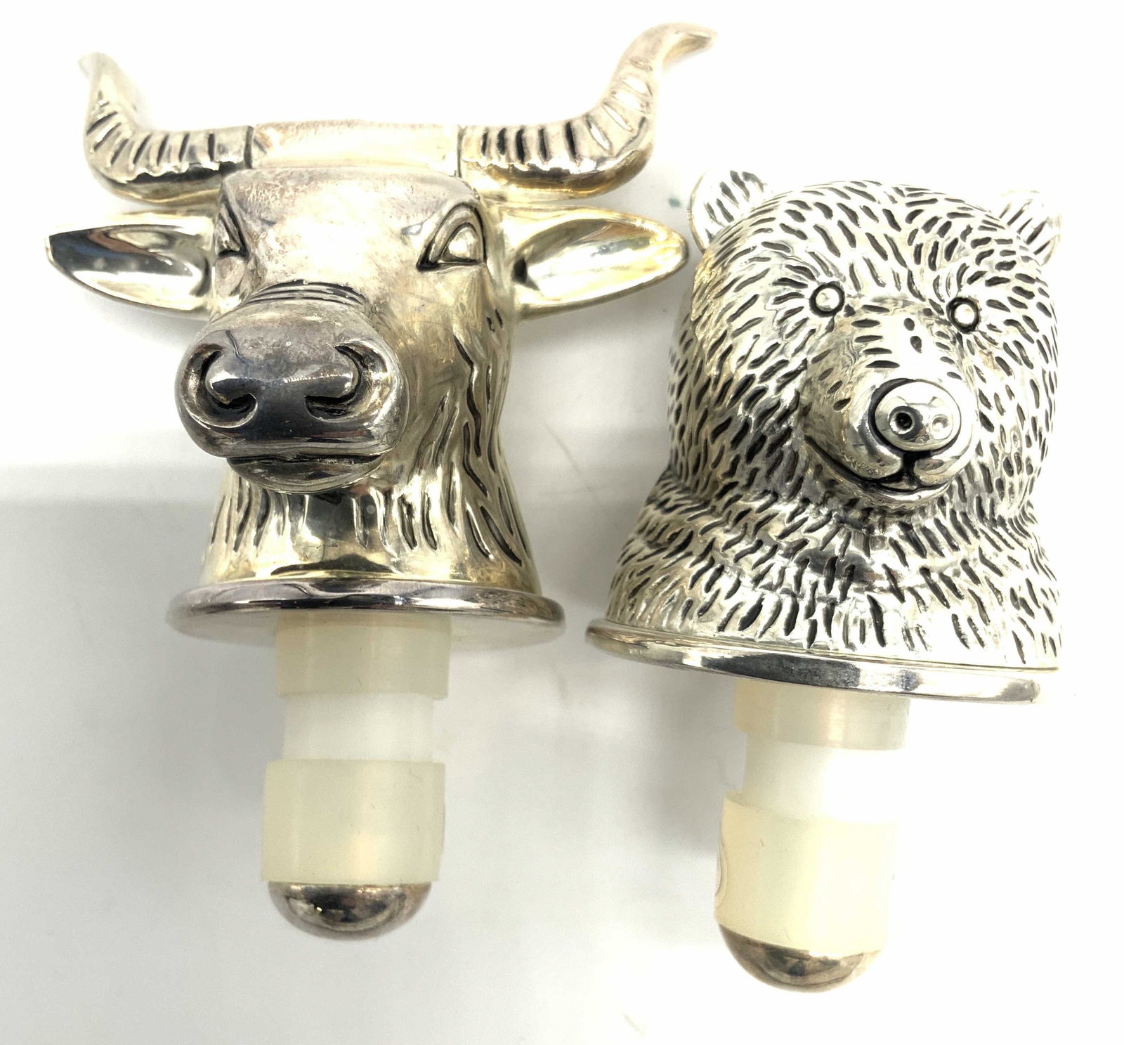 Group Lot 2 Metal Animal Wine Bottle Toppers: 2 wine bottle toppers made of metal, shaped into the heads of a bear and a bull, with etched detailing. Weighted. Largest measures Approx 3.75 in tall. Condition is consistent with age and use. Kitche