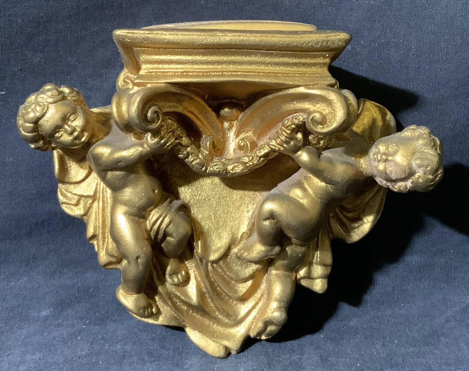 Gold Toned Cherub Wall Plinth: Gold Toned Cherub Wall Plinth, no apparent inscriptions or mark to piece, subject ceramic gold toned wall plinth, measures 5 1/2 x 6 x 2 1/2 inches, surface wear to piece. Artwork, fine art, wall art,