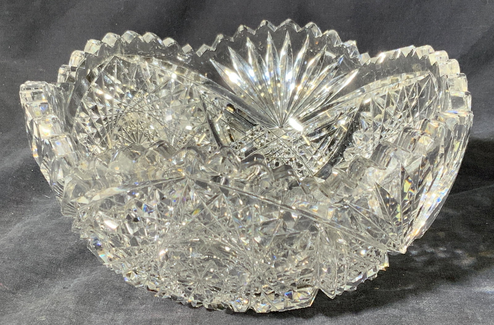 Hand Cut Vintage Saw Toothed Crystal Bowl: A hand cut thick rimmed crystal bowl with saw tooth cut rim, with hand cut faceted designs throughout exterior with checkered designs on base. Approximately 4 in tall and 8 in wide. Some chipping to c