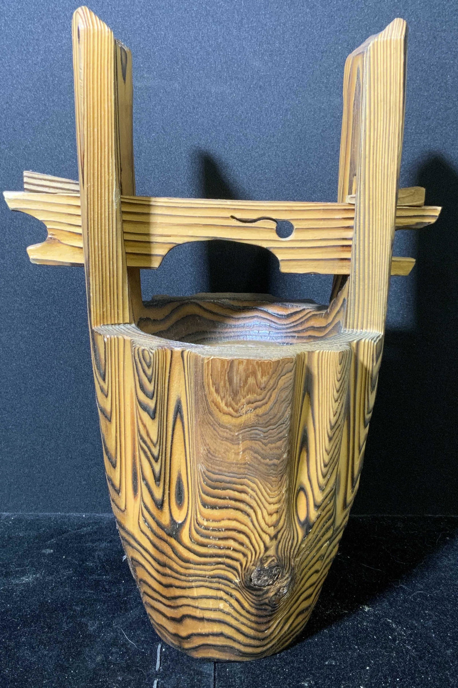 Wooden Bucket Formed Vessel: Wooden vessel. Carved to resemble a bucket. Houses a copper, cup like vessel Wear is consistent with age and use. Measures approx 13.5 inches h and 8.75 inches w. Bucket, carved wood, wooden accessori