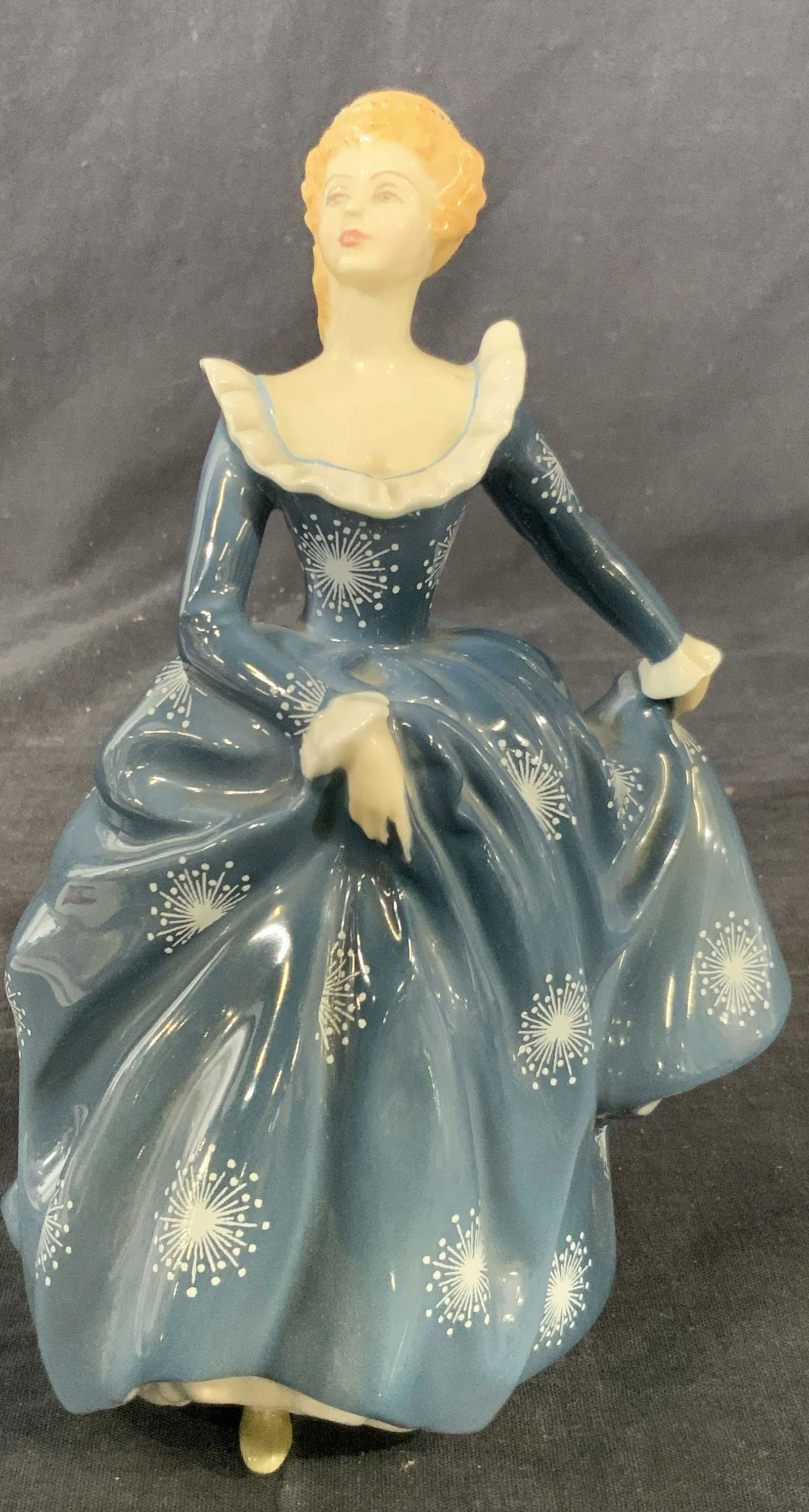 ROYAL DOULTON Porcelain Figurine Fragrance: A fine bone porcelain figurine Hallmarked ‘Royal Doulton England’ on underside marked with the name ‘Fragrance H.N. 2334’ depicting a woman in a blue painted dress with white star designs, wit