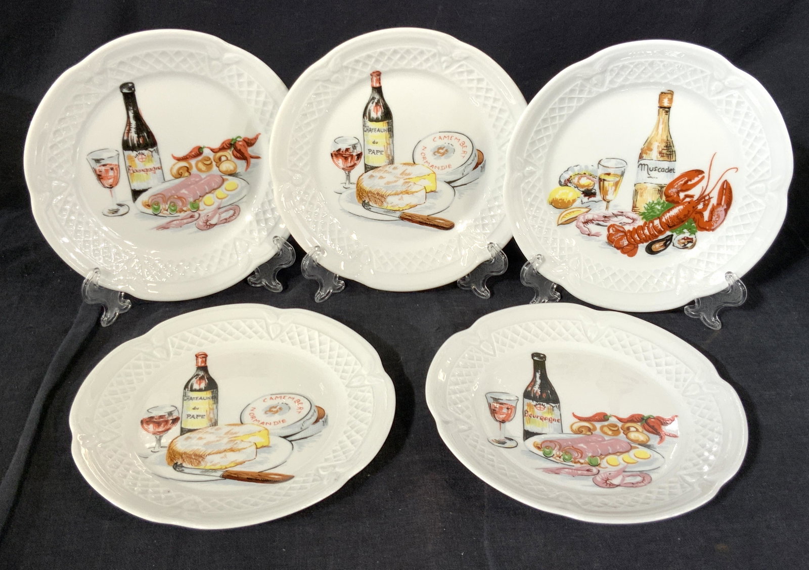 Set of 5 LOURIOUX Porcelain Plates: A set of 5 small hand painted porcelain plates marked ‘Lourioux’ & ‘Porcelaine’ on underside of each. All plates have a hand painted scene of food and wine, ranging from cheeses, seafood and m