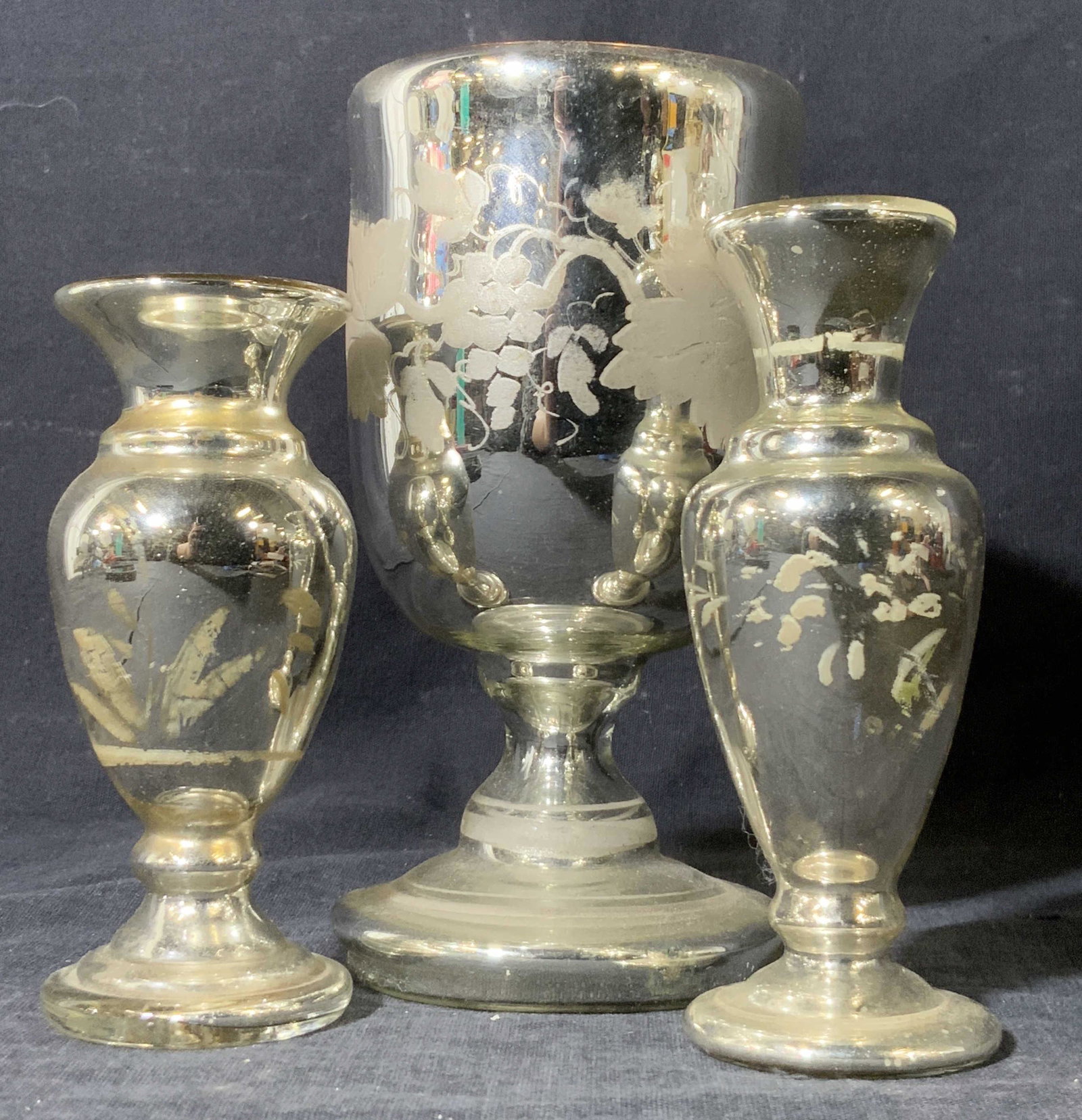 Lot 3 Vintage Mercury Glass Vessels, Vases & More: Three vintage Mercury glass vessels. One vessel is a Mercury glass goblet with a grapevine motif along the sides. Interior is an amber tone. Appears to have a pontil to the underside. Measures approx 
