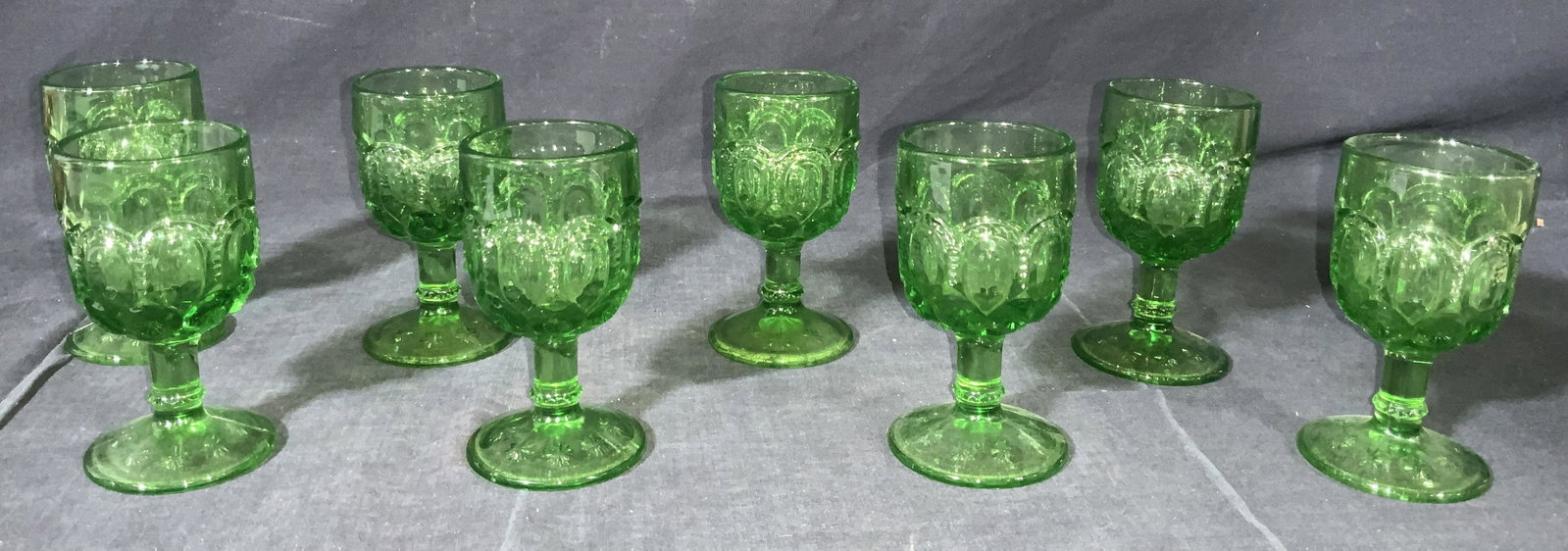 Set Of 8 Emerald Green Vintage Wine Glasses: A set of 8 Vintage emerald green Moser style wine glasses with embossed design with ribbed raised pattern and star like imprints on exterior of cup and base of cup. Approximately 4.5 in tall. Conditio