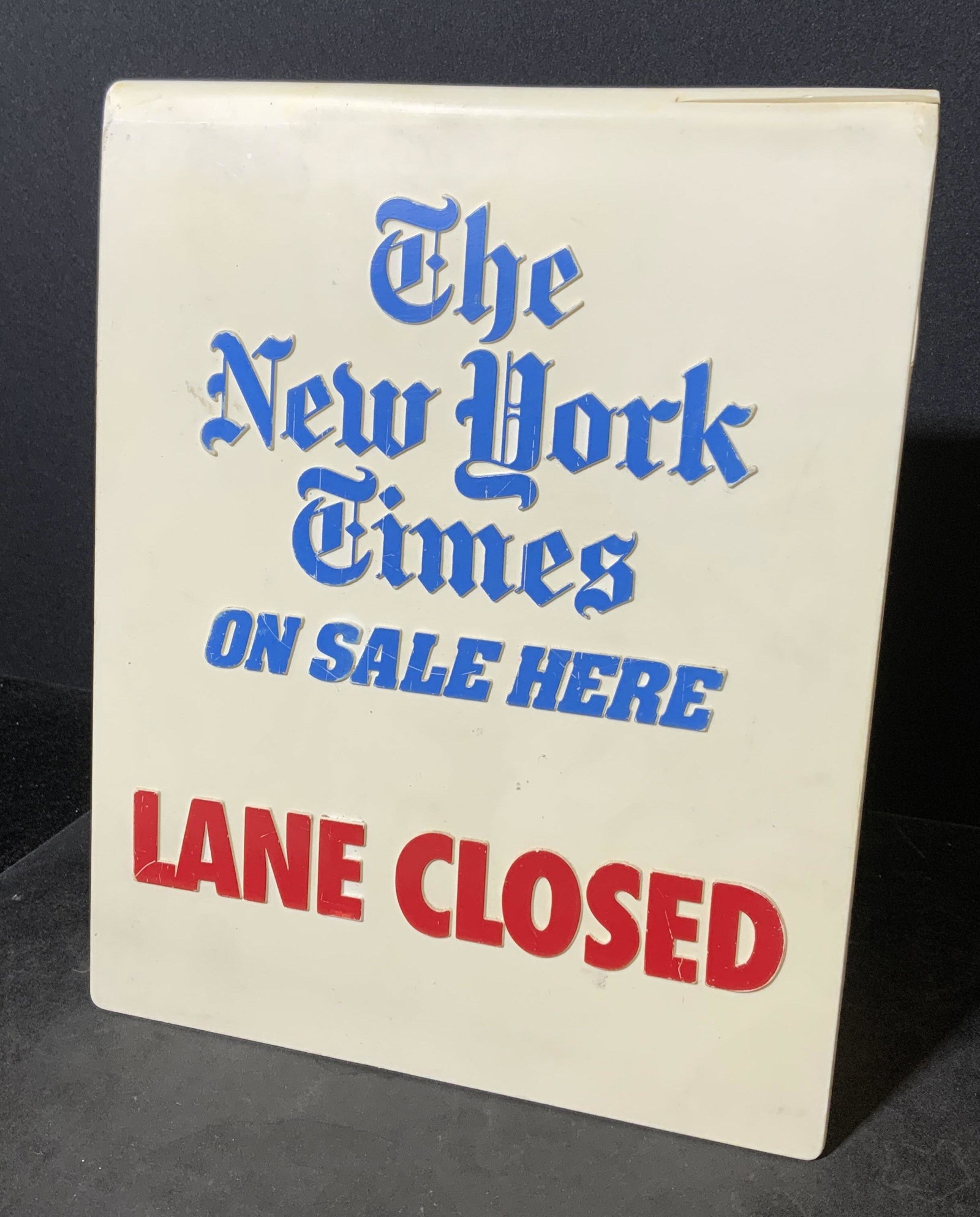 NEW YORK TIMES Lane Closed Sign: Lane closed sign, reads as THE NEW YORK TIMES ON SALE HERE LANE CLOSED. Sign is plastic, cracking present. Appears to be vintage. Measures approx 10 inches h and 8 inches w. Home decor, decorative art