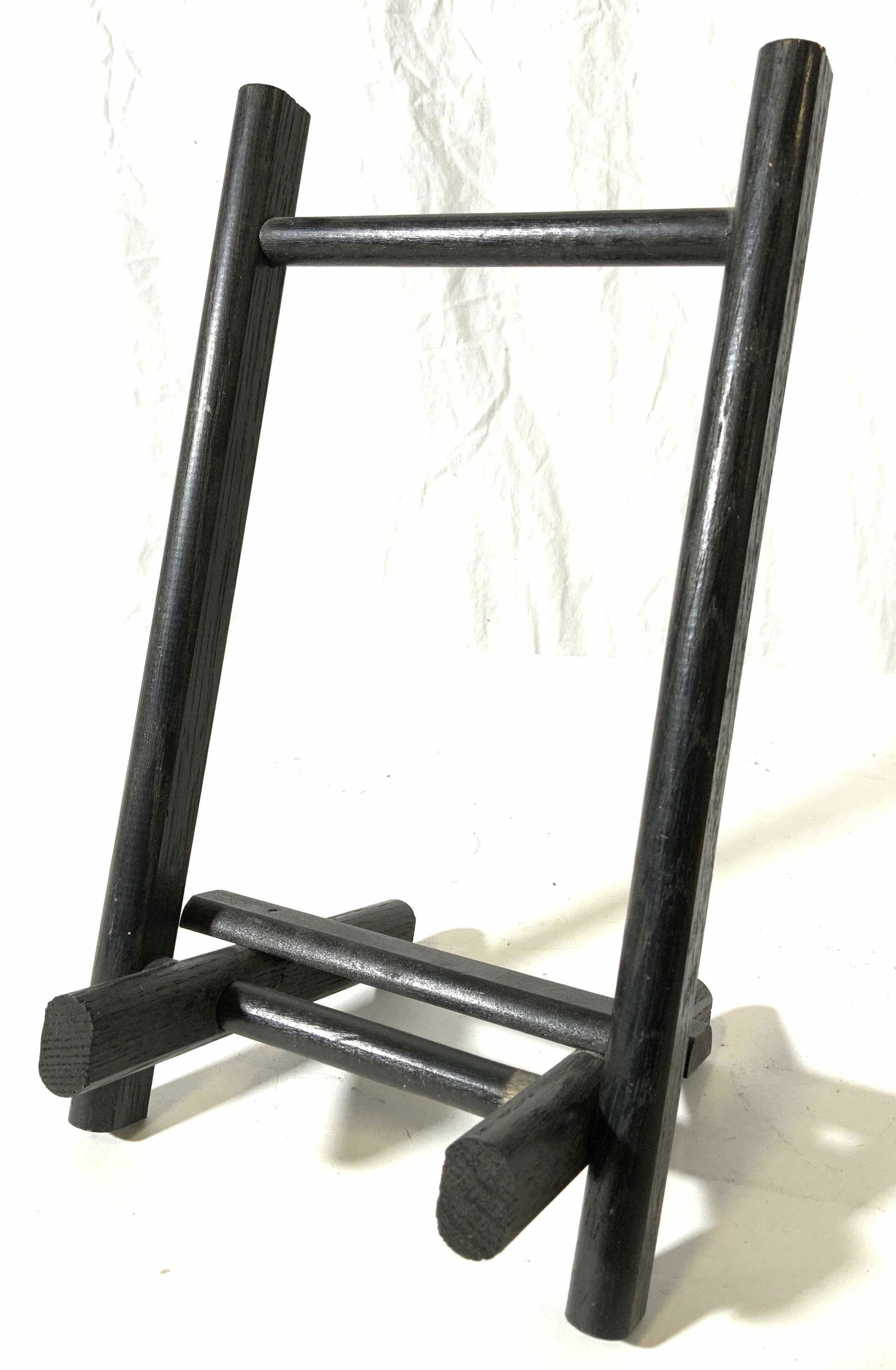 Black Toned Wooden Table Easel: Easel is black toned and wooden possibly veneer. Piece appears to be vintage. Easel folds for easy storage. Piece when set up measures approx 11 inches tall 6.5 inches wide 6 inches deep. Easel, woode