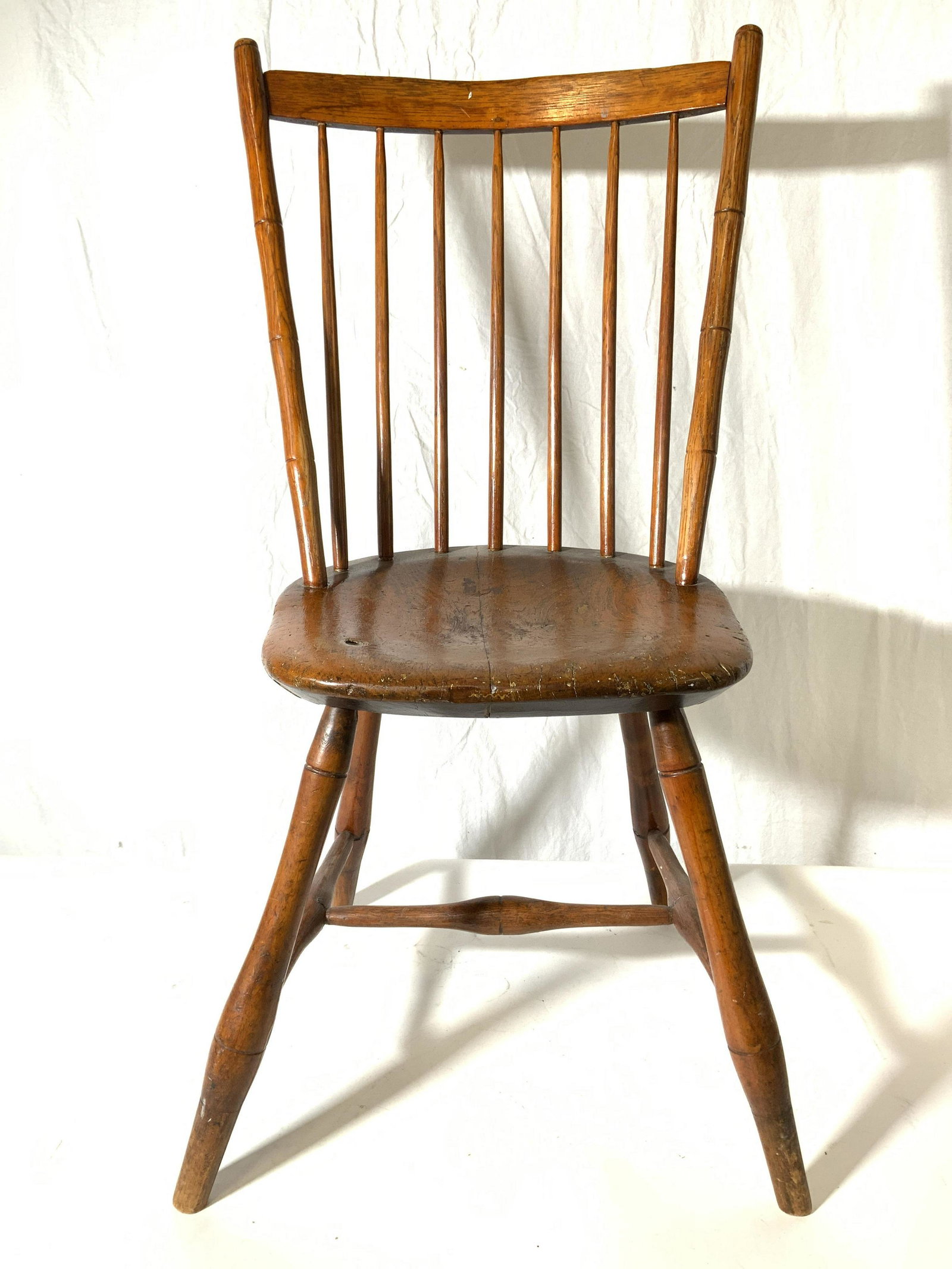 Vintage Carved Wooden Spindleback Chair: Chair is vintage possibly antique. Piece is wooden, appears to possibly be hand crafted. Chair has spindle backrest. Piece has 4 legs with H shaped stretcher in between. Piece measures approx 36 inche