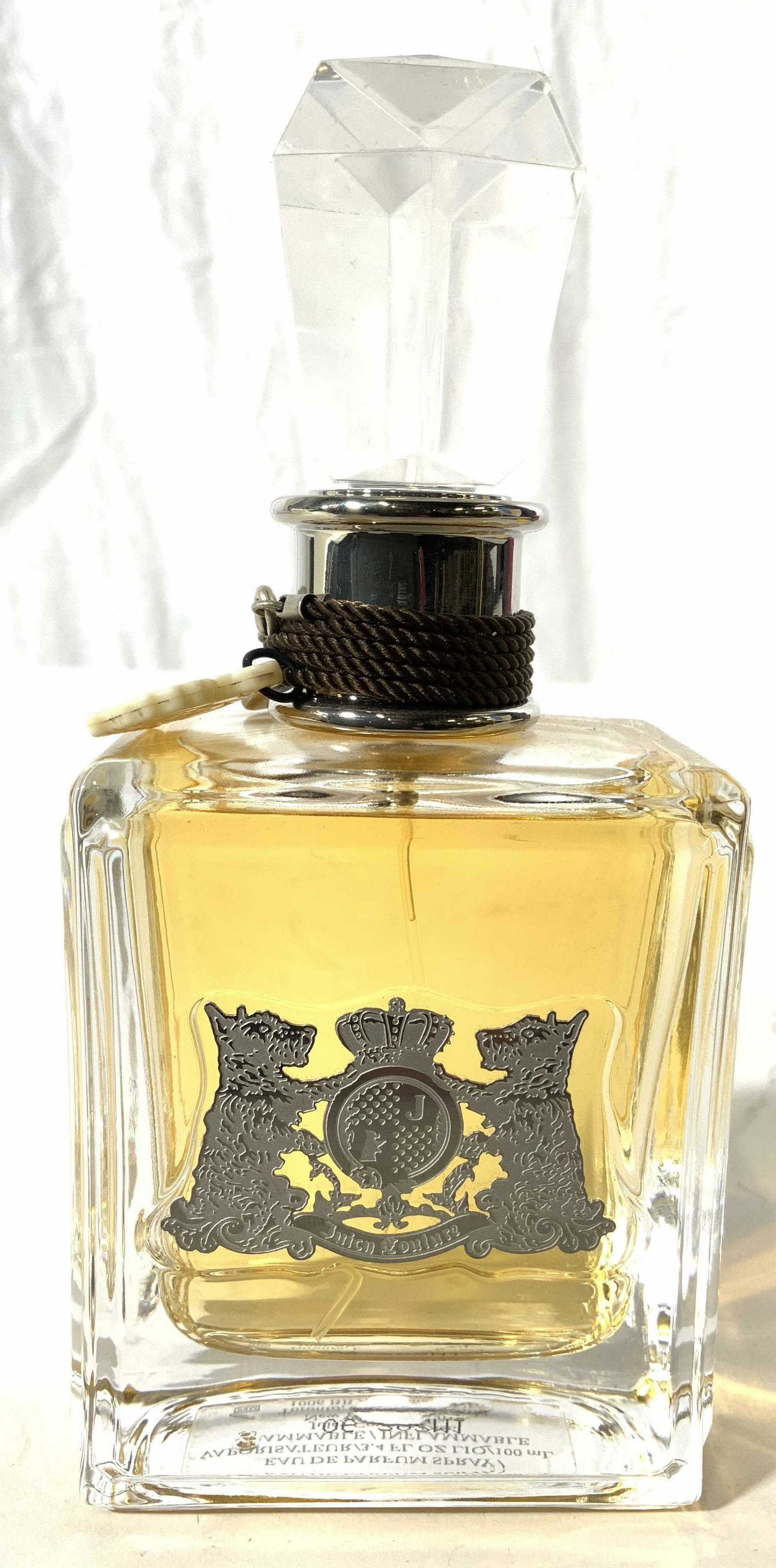 JUICY COUTURE Perfume In Bottle: Front side of piece has dog figure & crown emblem which reads JUICY COUTURE. Perfume bottle is partially full. Piece measures approx 6 inches tall 2.75 inches wide. Perfume, perfume bottle, women’s 