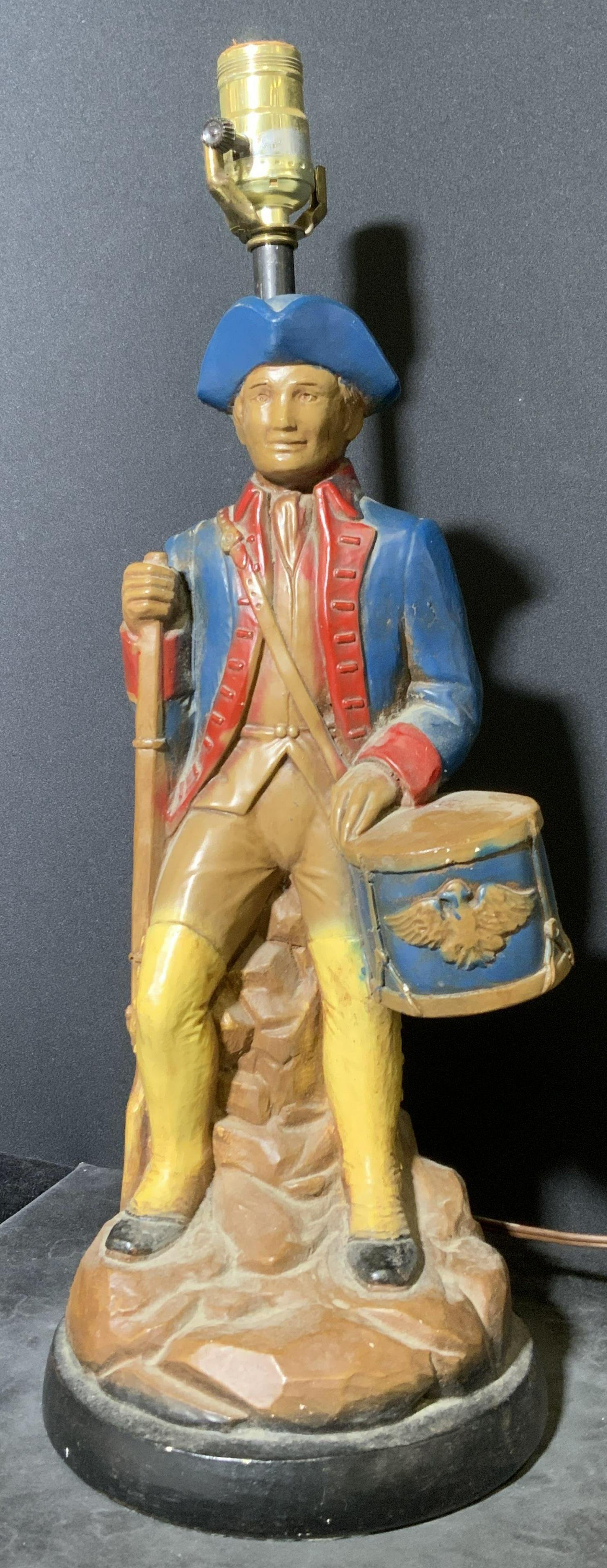 Ceramic Vintage Revolutionary War Soldier Lamp: Ceramic lamp, appears to be vintage. Depicts a revolutionary war soldier, holding a musket, a drum is strapped to him. Wear is consistent with age and use. Measures approx 19.75 inches h, 6 inches w.