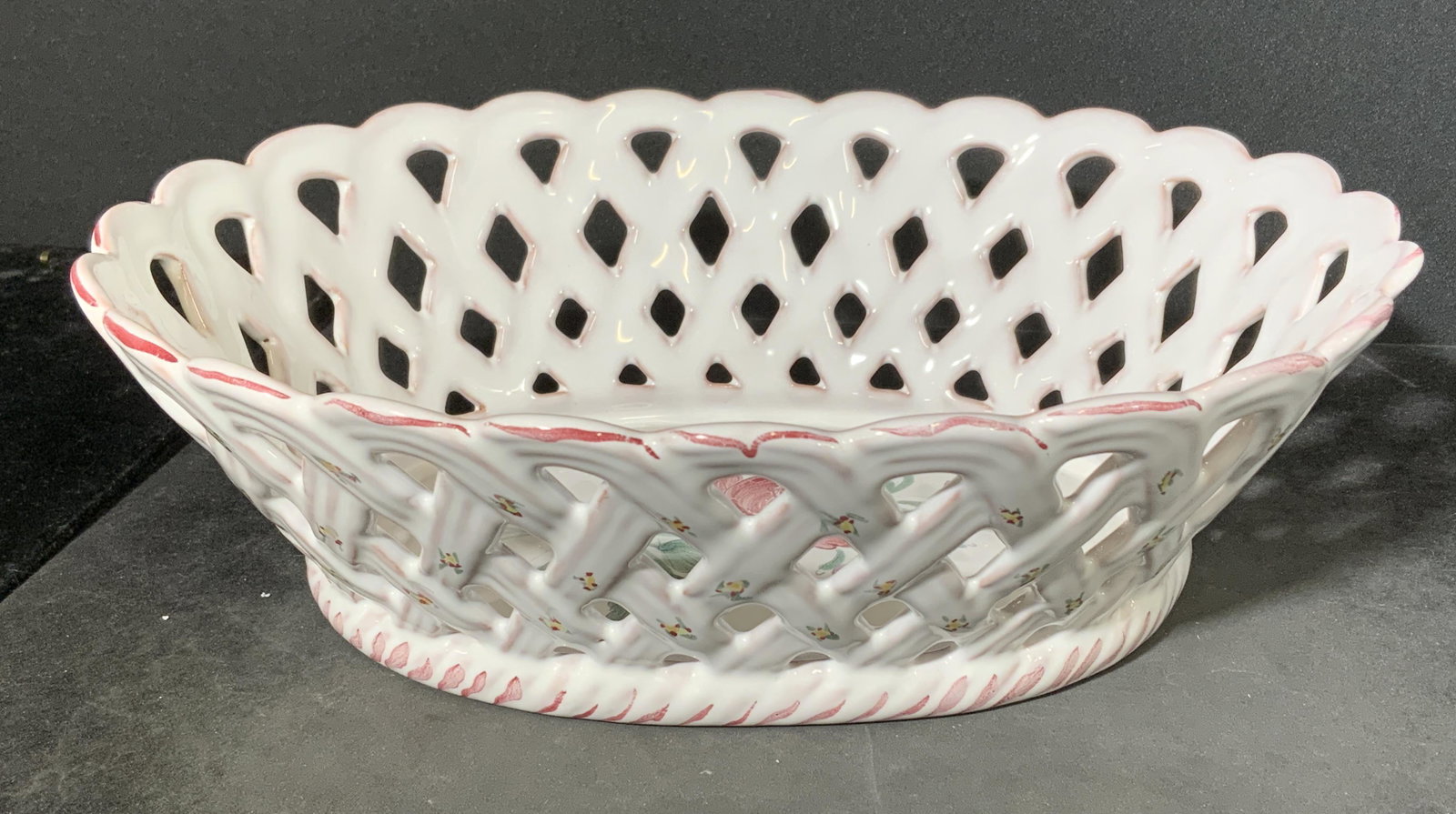French Faience Pierced Earthenware Bowl: Hand painted earthenware bowl. Decorated with floral patterns in well of bowl. White craze on terra cotta toned pottery. Underside signed, in French. Measures approx 3 inches h, 9.5 inches w. French p