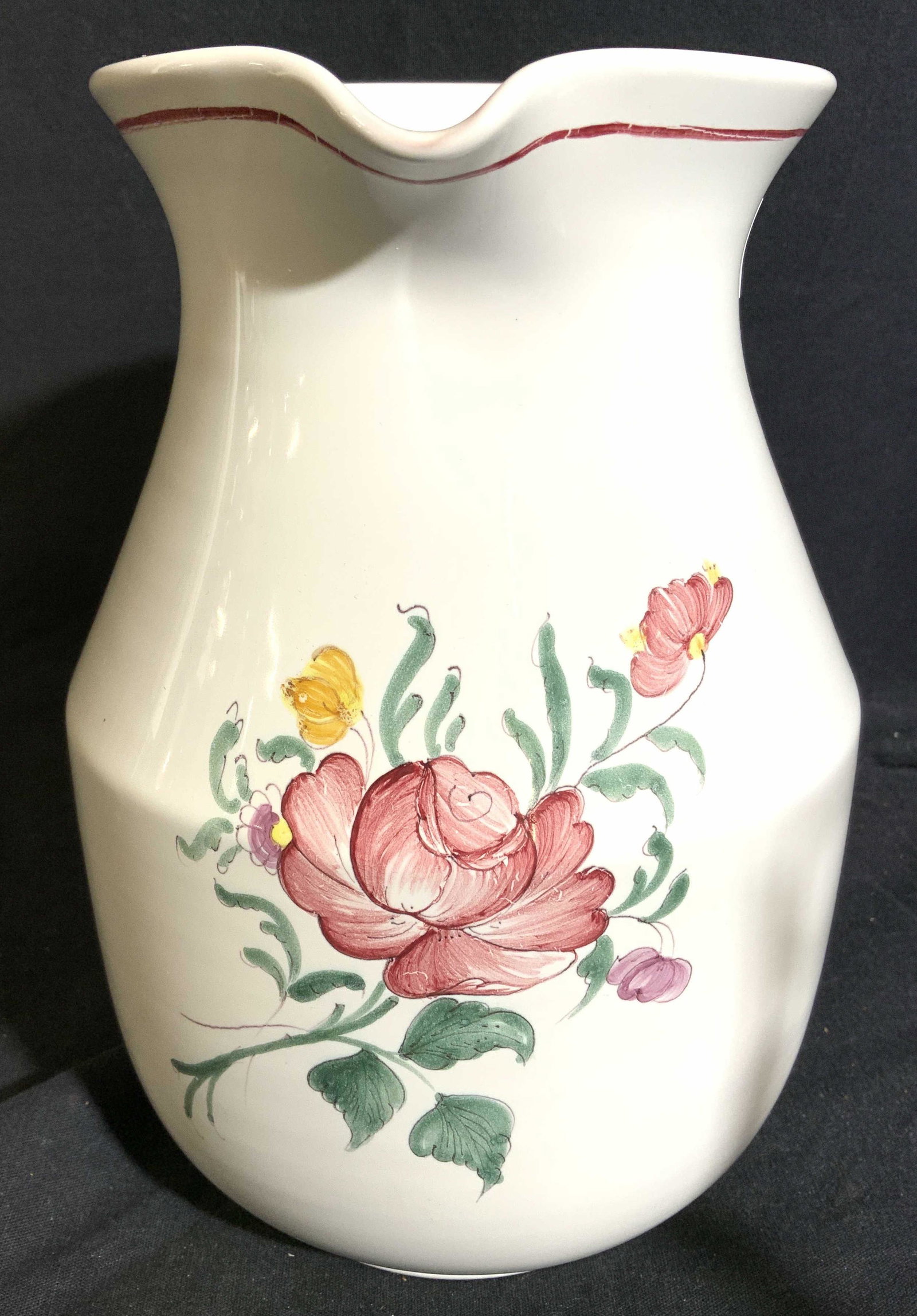 ATELIER MOUSTIERS Footed Porcelain Pitcher: Underside of pitcher is marked ATELIER DE SEGRIES a MOUSTIERS FRANCE DY 539. Pitcher is white toned with multi toned floral and leaf detail. Pitcher measures approx 9 inches tall 6 inches wide 8 inche