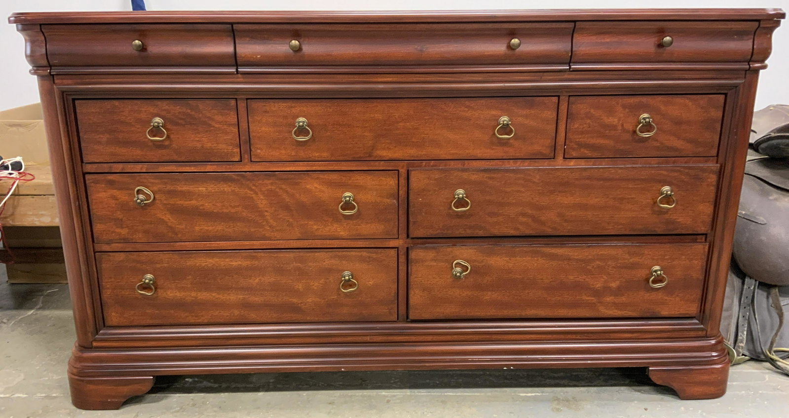 Wooden 10 Drawer Sideboard: Sideboard has 10 drawers each with dangling gold toned metal handles with appear to possibly be brass. Piece is mahogany toned and appears to be wooden, possibly veneer. Piece measures approx 68 inche