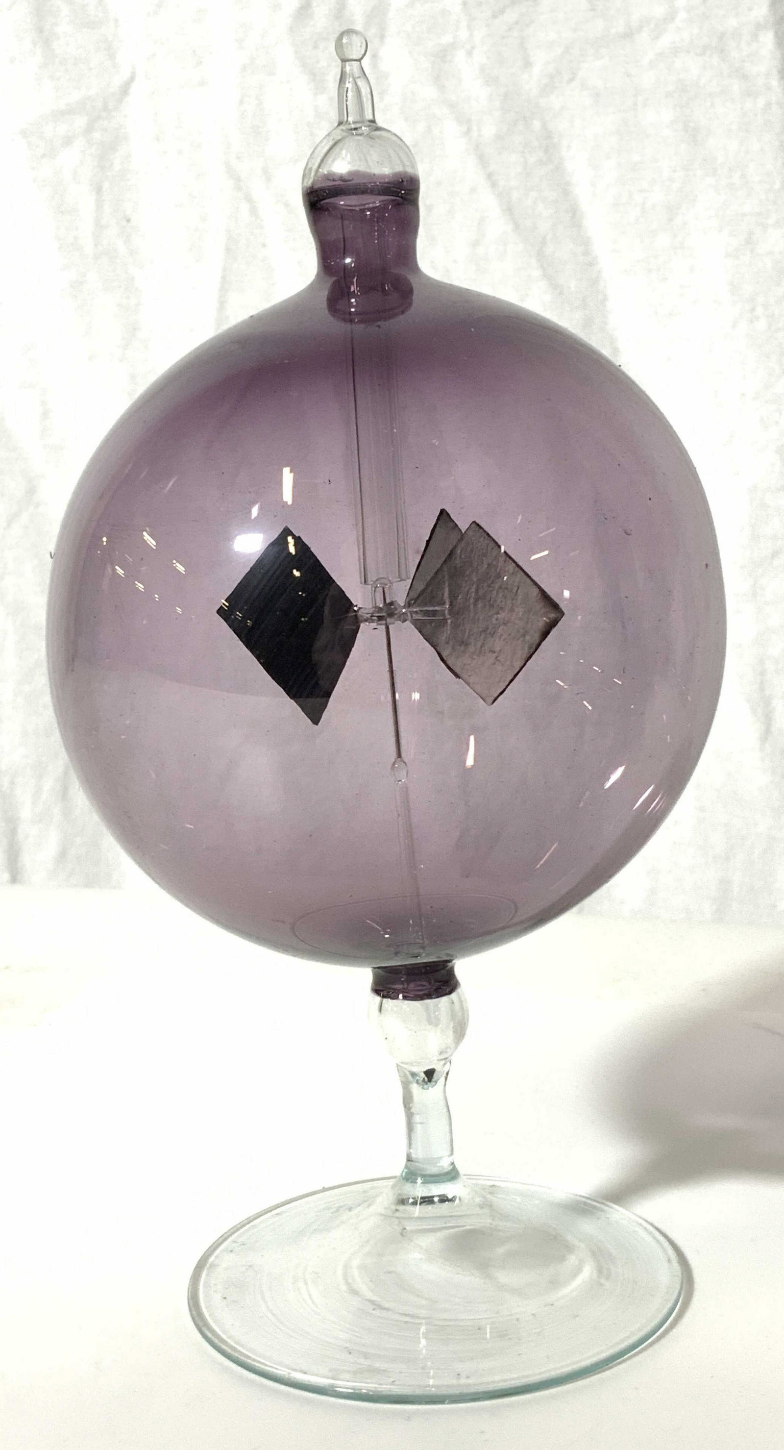 Mobile Encased In Purple Glass Orb: Mobile Encased In Purple Glass Orb, no apparent inscriptions or mark to piece, translucent purple glass orb with clear glass base and finial encasing a 4 point mobile, measures 7 1/2 inches tall, surf