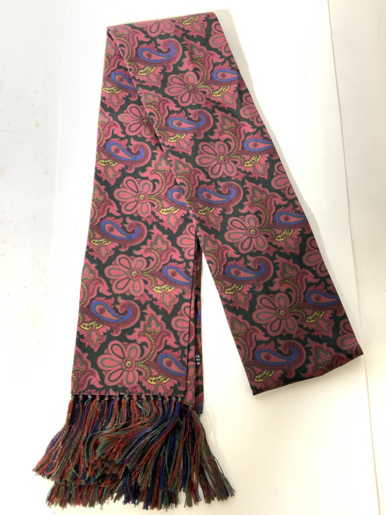 DRAKES Silk Scarf, England: A silk scarf by Drakes, with fringe. Has tags that read Drakes London and Hand printed, 100% Silk, Made in England Scarf has a black toned base with intricate paisley-like design made of red with acce