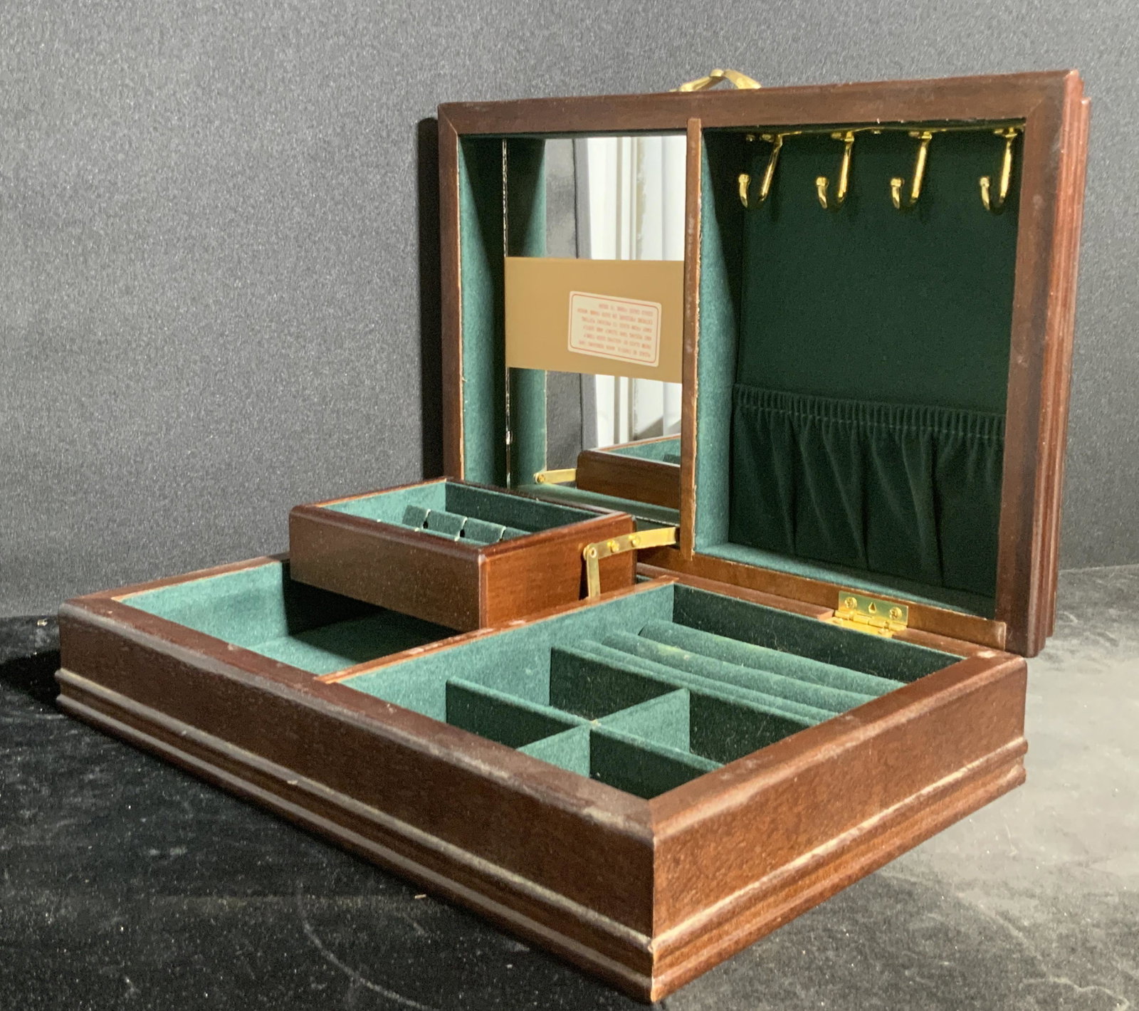 POWELL Vintage Wooden Jewelry Box: A rich brown hued jewelry box with a deep green velvet style interior. Gold tone metal hardware. Places to put rings, necklaces, earrings, and more. Mirror to interior. Underside possesses a sticker t