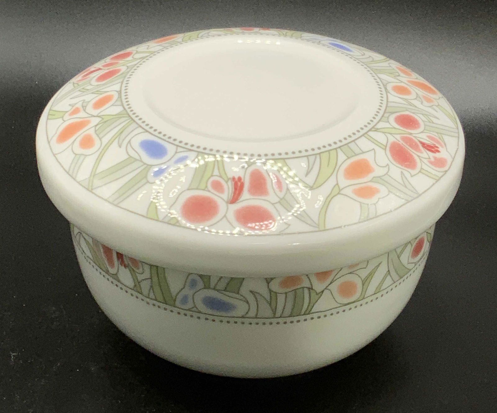 FASHIONWARE Snow Bone China Lidded Trinket Box: A white bone china trinket box with lid. Banded floral patterns along lid and base. Florals are primarily red, orange, blue, and green hues. Underside reads Fashionware, Snow Bone China. Measures appr