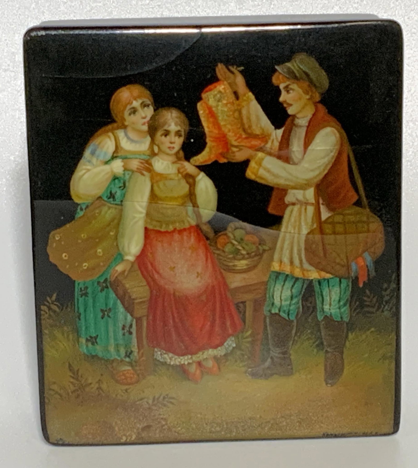 Collectible Russian FEDOSKINO Lacquer Box: Hinged Box with black exterior with decorative ribboning at base and a street vendor selling attempting to sell boots to a mother and daughter, Signed under lid and comes with FEDOSKINO certificate, M